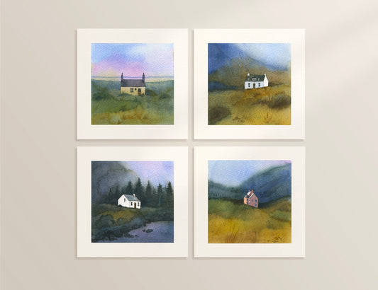 Four framed watercolor paintings of houses in scenic landscapes on a wall.