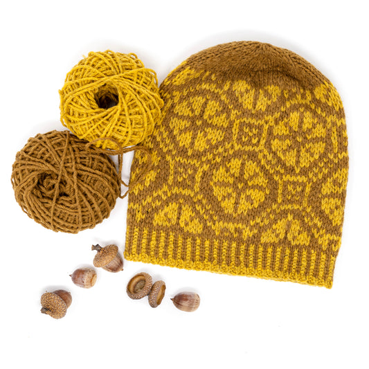 Ratas Fair Isle hat with carriage wheel motif accompanied with yarn balls and acorns
