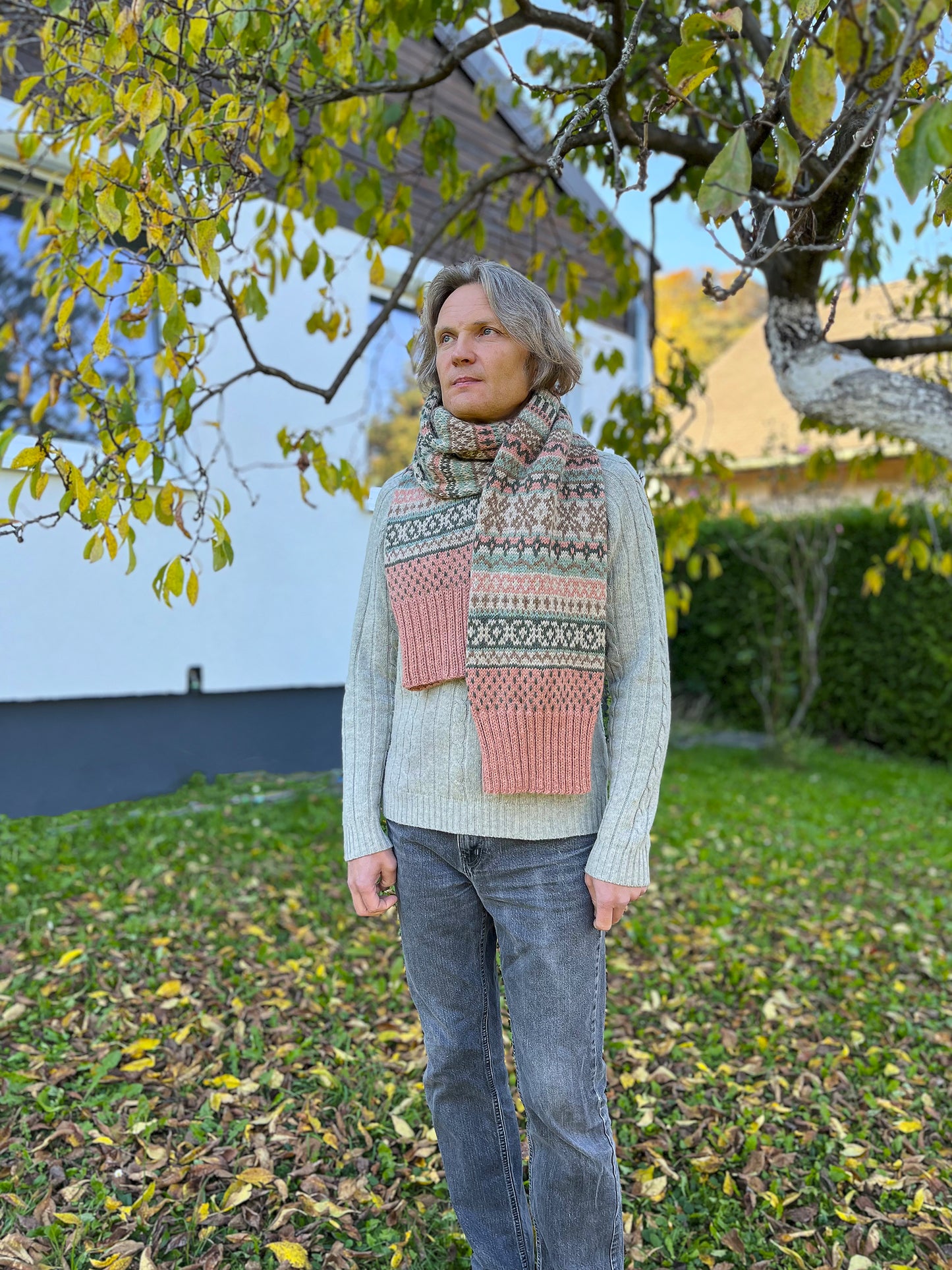 A man wearing Rohukuela Fair Isle scarf standing in an autumn garden