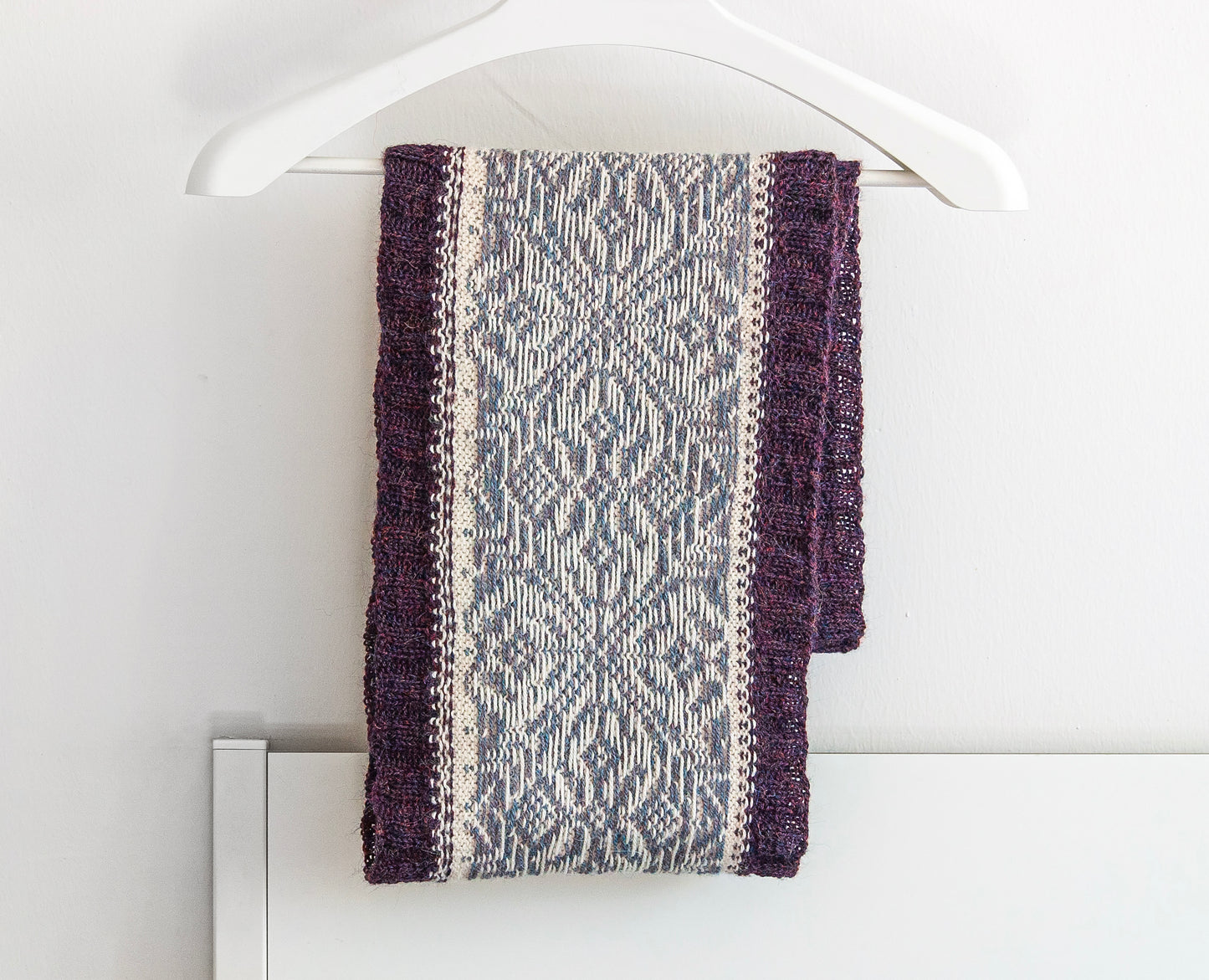 Hand-knitted alpaca infinity scarf with a purple, gray and cream snowflake pattern  displayed inside out