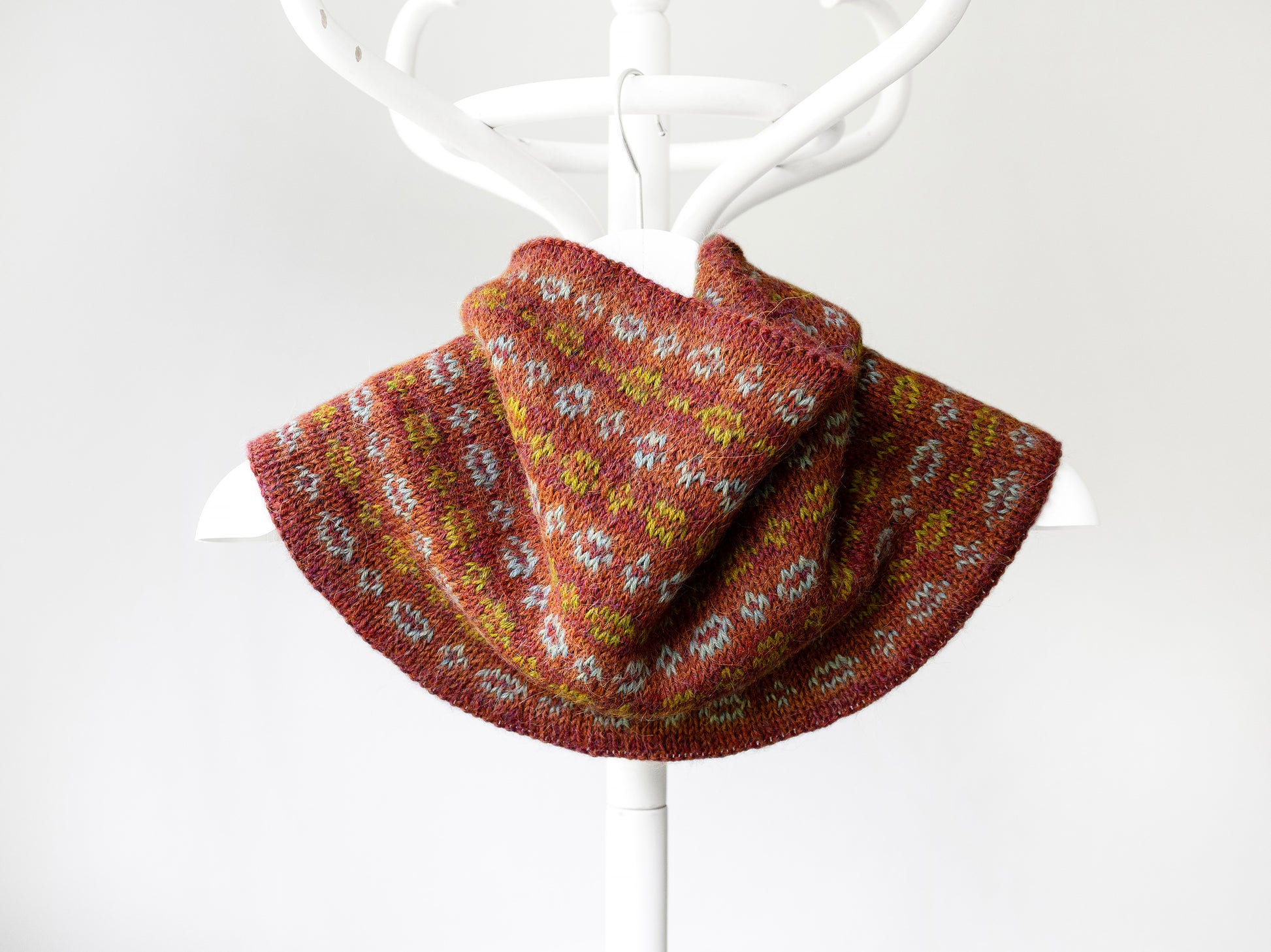 A hand-knitted cowl neck warmer with a multicolor Fair Isle chains pattern