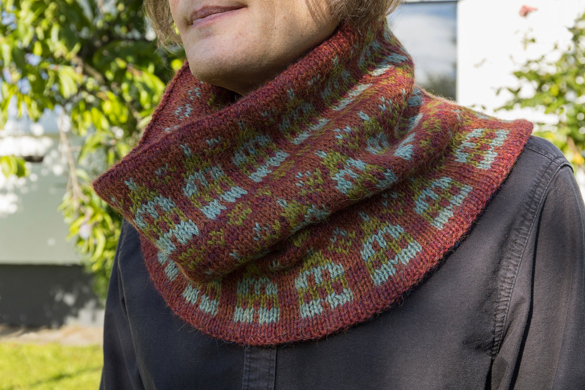 Person wearing Stortorget Fair Isle cowl with houses motif outdoors