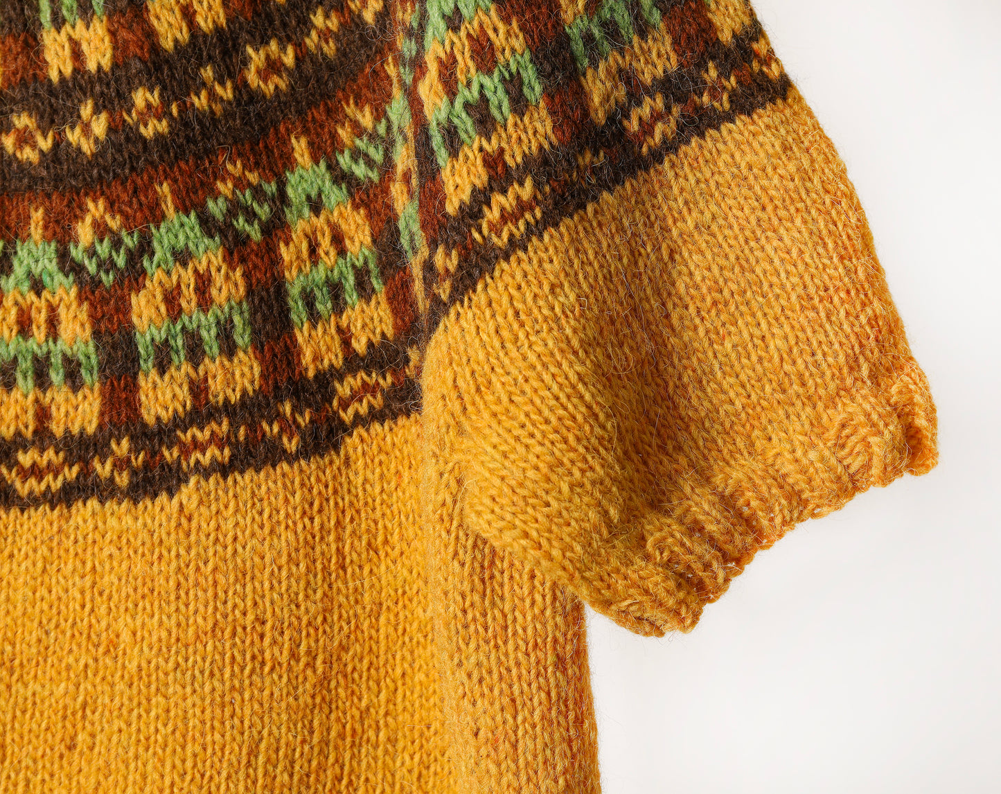 Close-up of a knitted sweater with a nordic houses yoke pattern on a white background