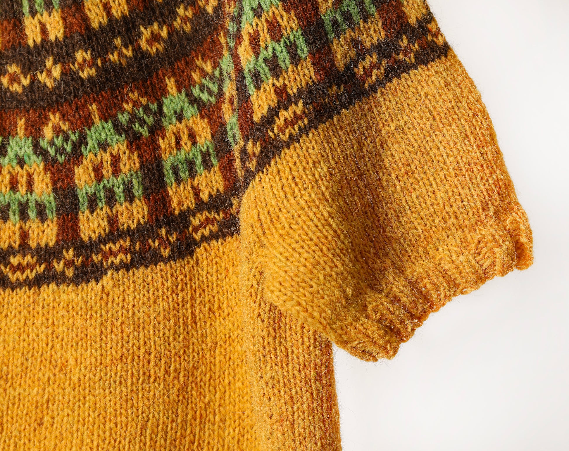 Close-up of a knitted sweater with a nordic houses yoke pattern on a white background