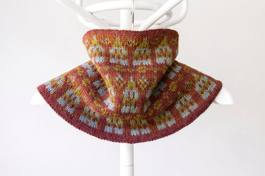 Knitted cowl with a nordic houses pattern on a white background