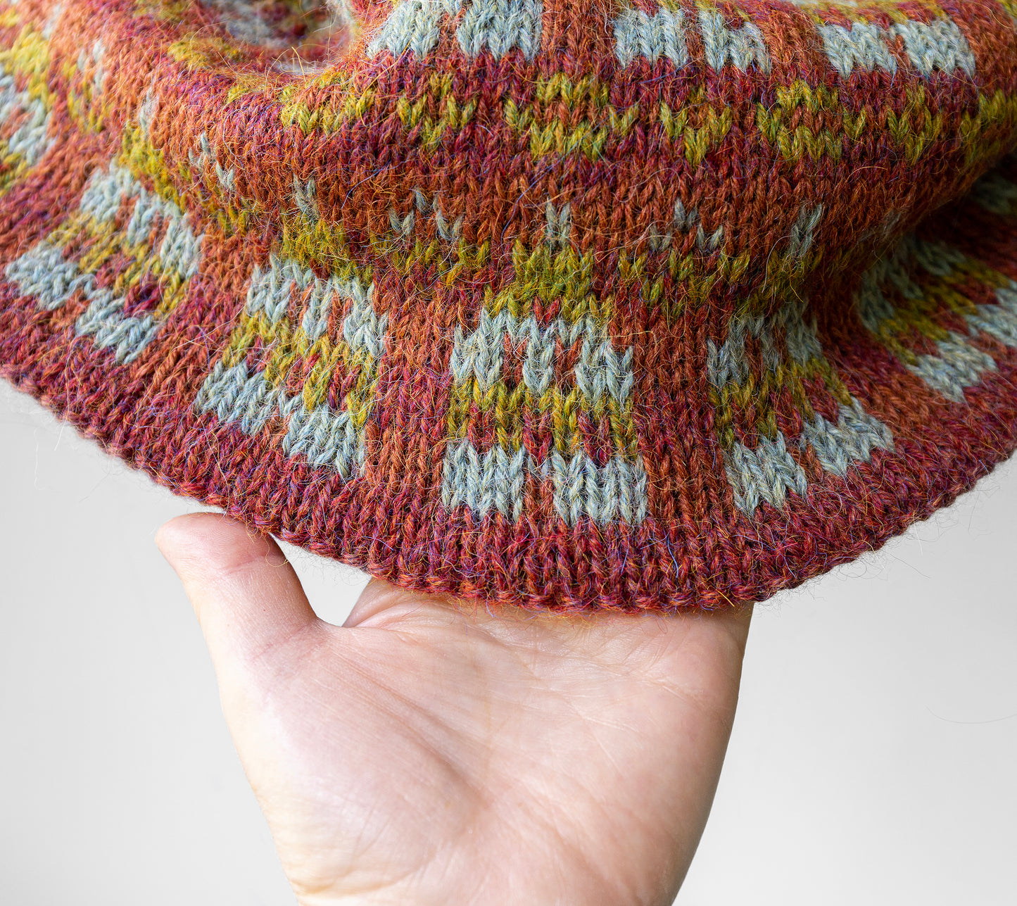 Close-up of a hand holding a knitted fabric with a pattern