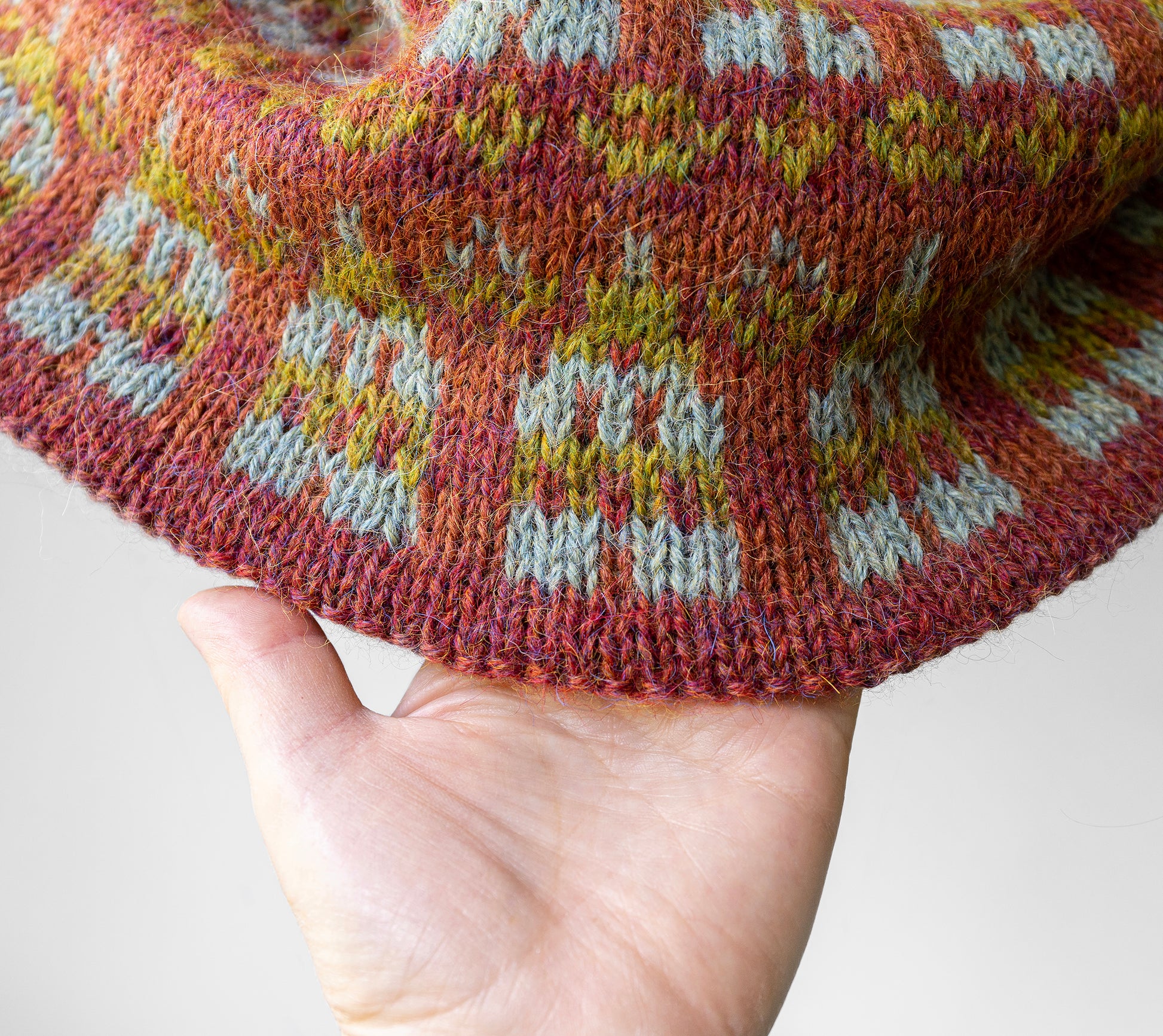 Close-up of a hand holding a knitted fabric with a pattern