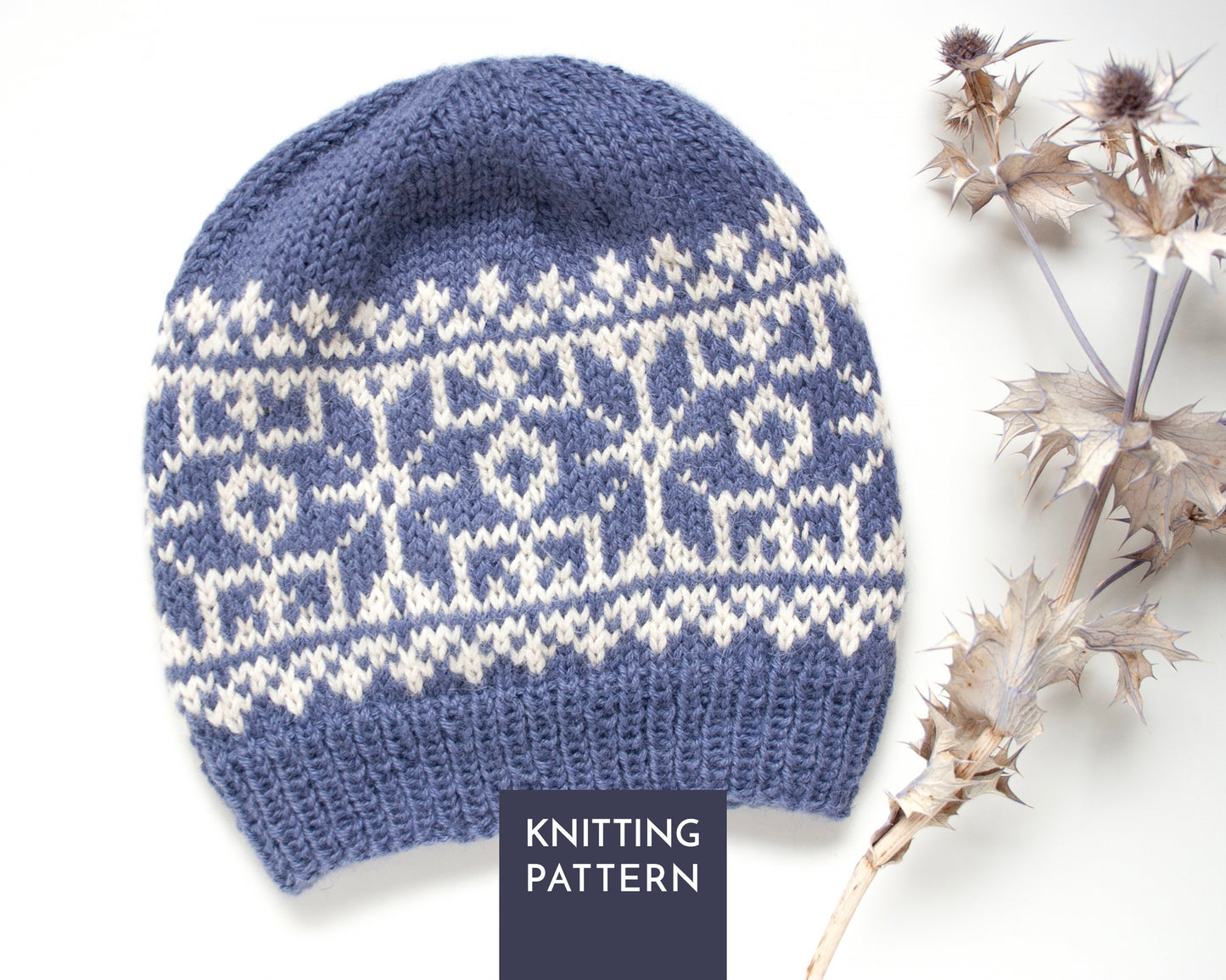 A blue and white knitted beanie featuring a geometric fair isle pattern. The hat has a ribbed brim and a rounded crown. A dark blue square overlay at the bottom centre contains the white text KNITTING PATTERN in capital letters.