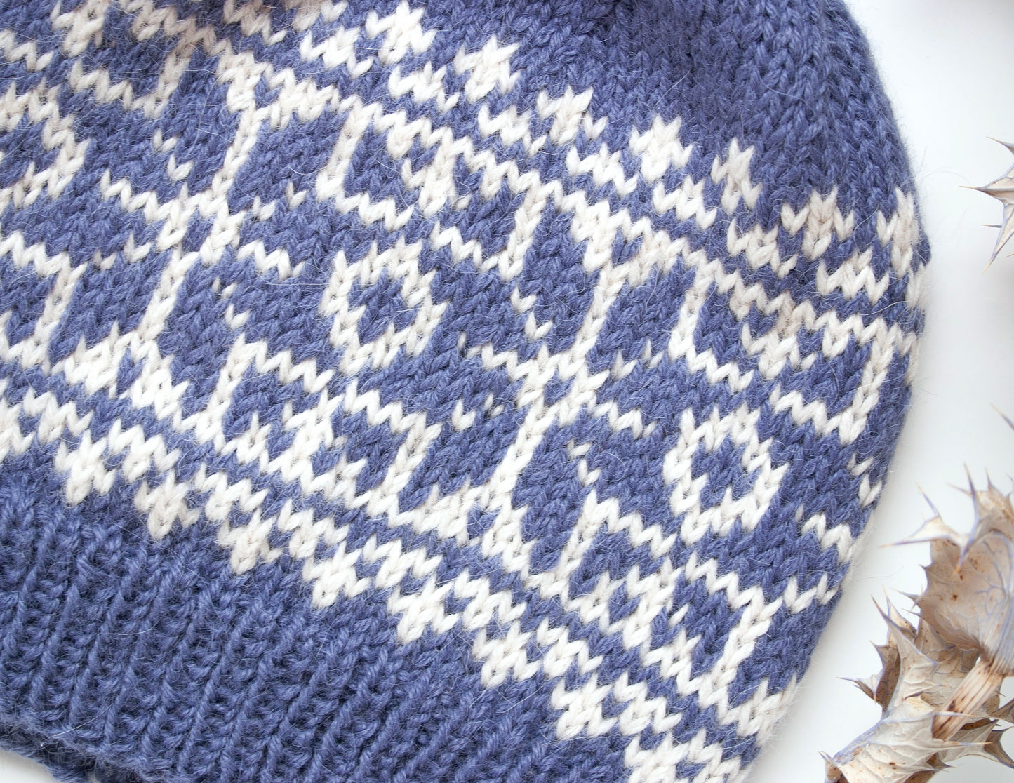 close up for blue and white alpaca wool hand-knitted Fair Isle beanie hat in snowflake knitting pattern