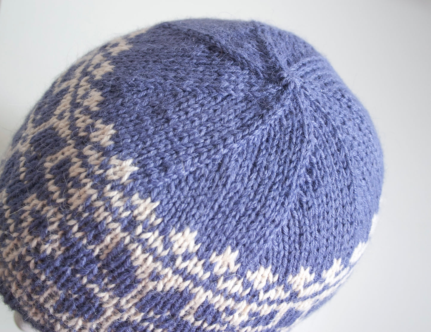 blue and white alpaca wool hand-knitted Fair Isle beanie hat in snowflake knitting pattern top view