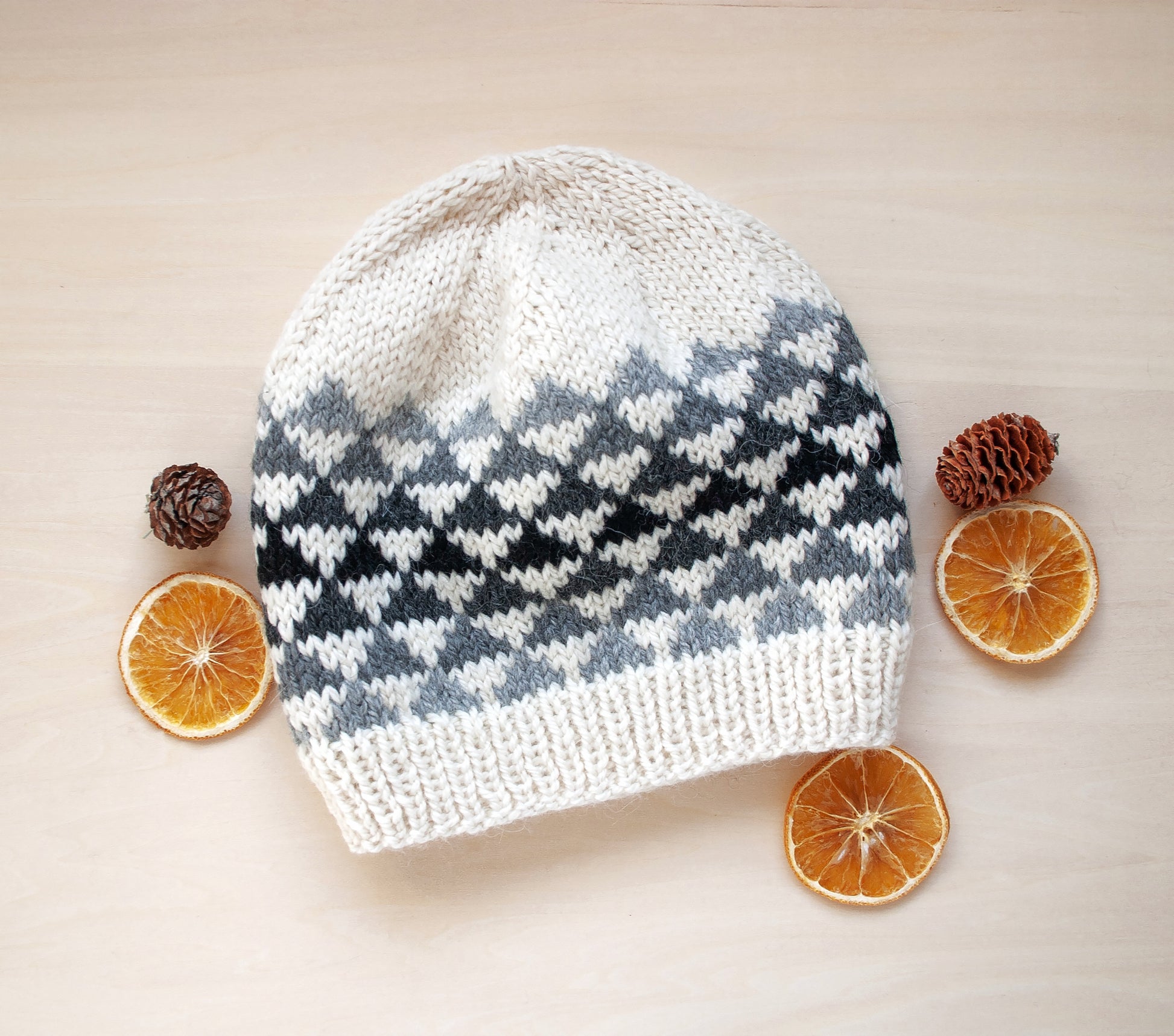 A white, grey and black wool hand-knitted Fair Isle beanie hat in triangles knitting pattern