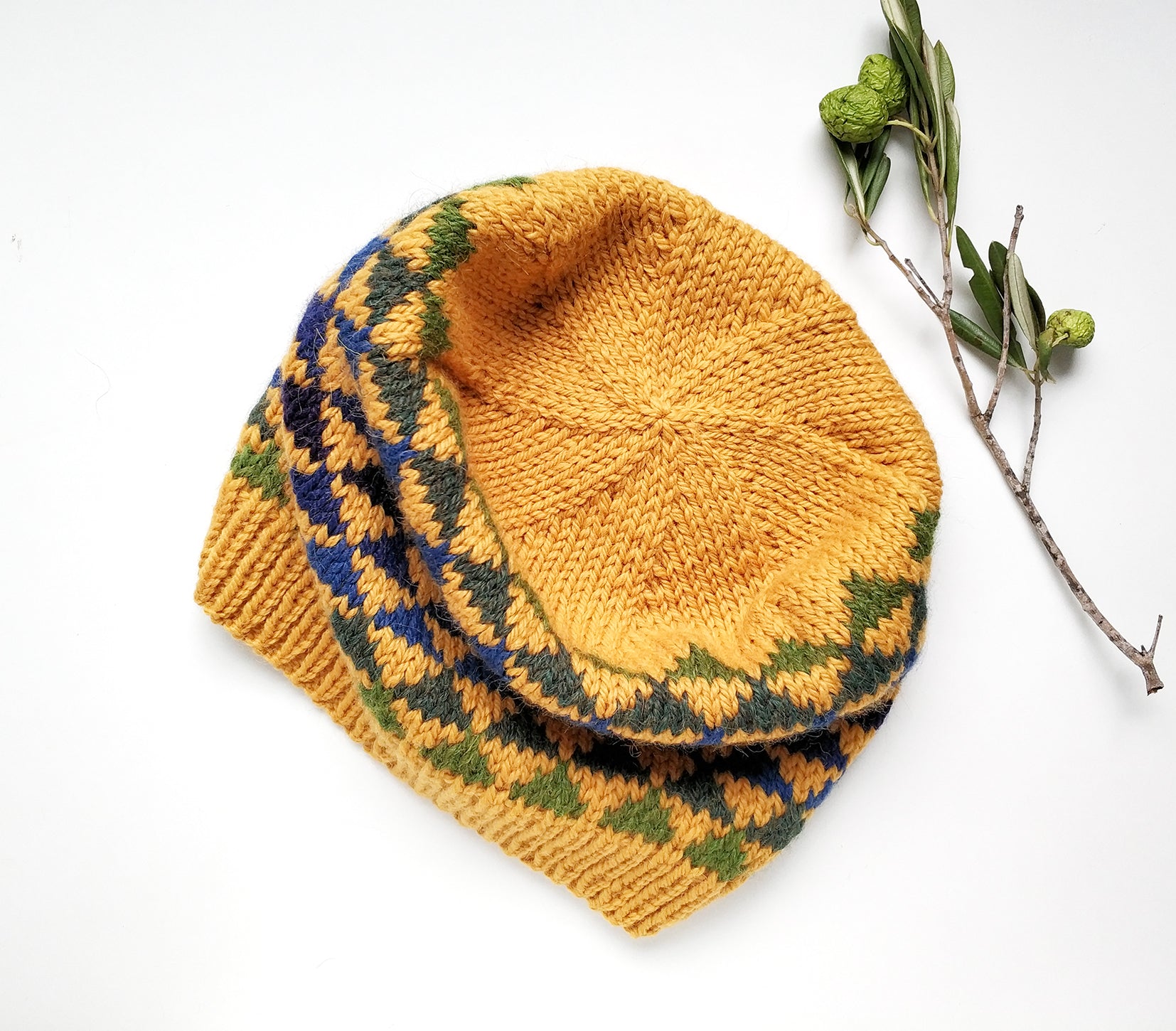 A crown of a yellow, blue and green wool hand-knitted Fair Isle beanie hat in triangles knitting pattern