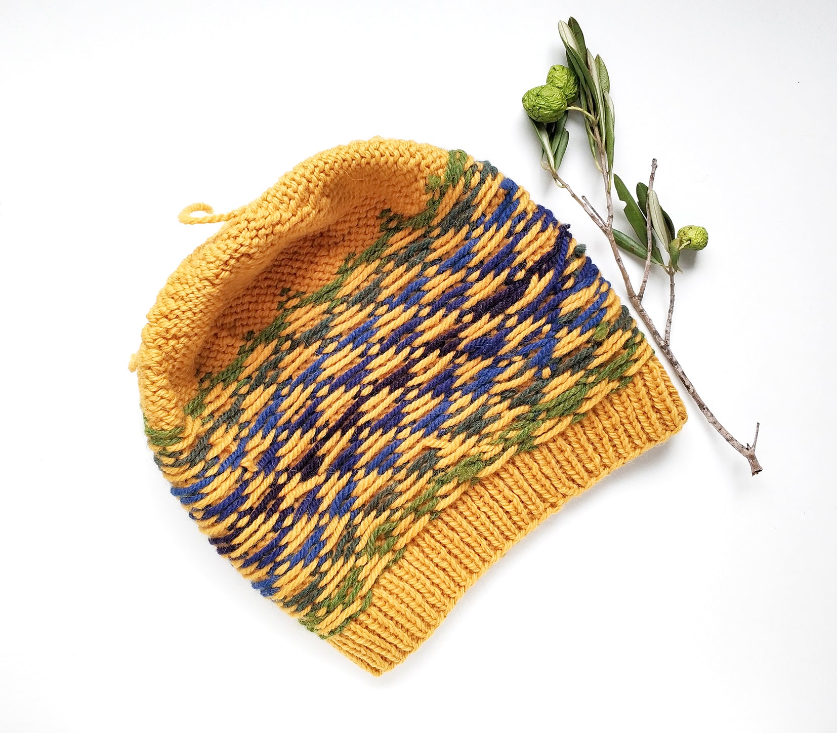 A yellow, blue and green wool hand-knitted Fair Isle beanie hat in triangles knitting pattern, inside out