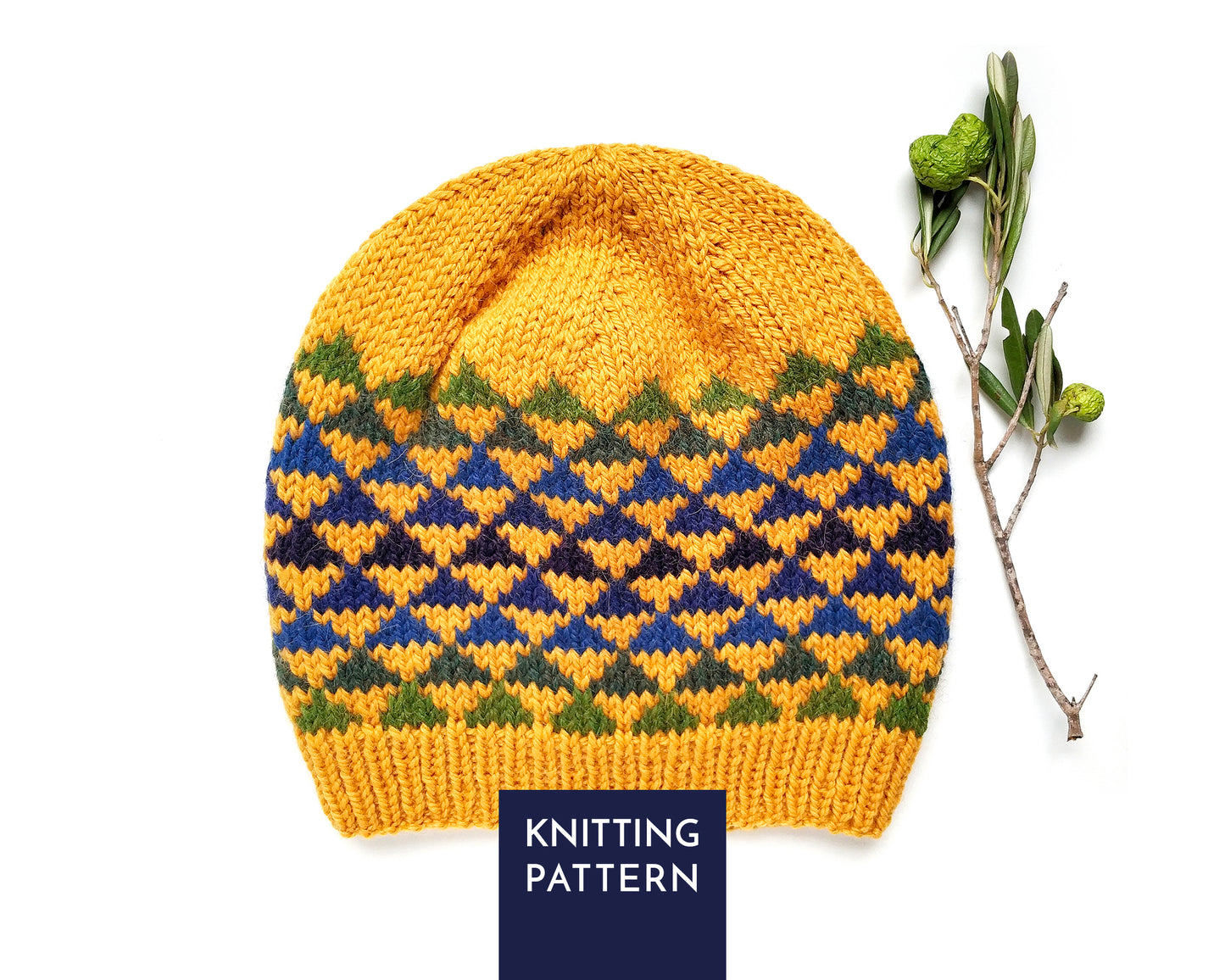 A knitted beanie hat shown flat on a white background, with a dark navy label reading 'KNITTING PATTERN' at the bottom. The hat is mustard yellow with a geometric triangles pattern band in blue, green, and dark navy.