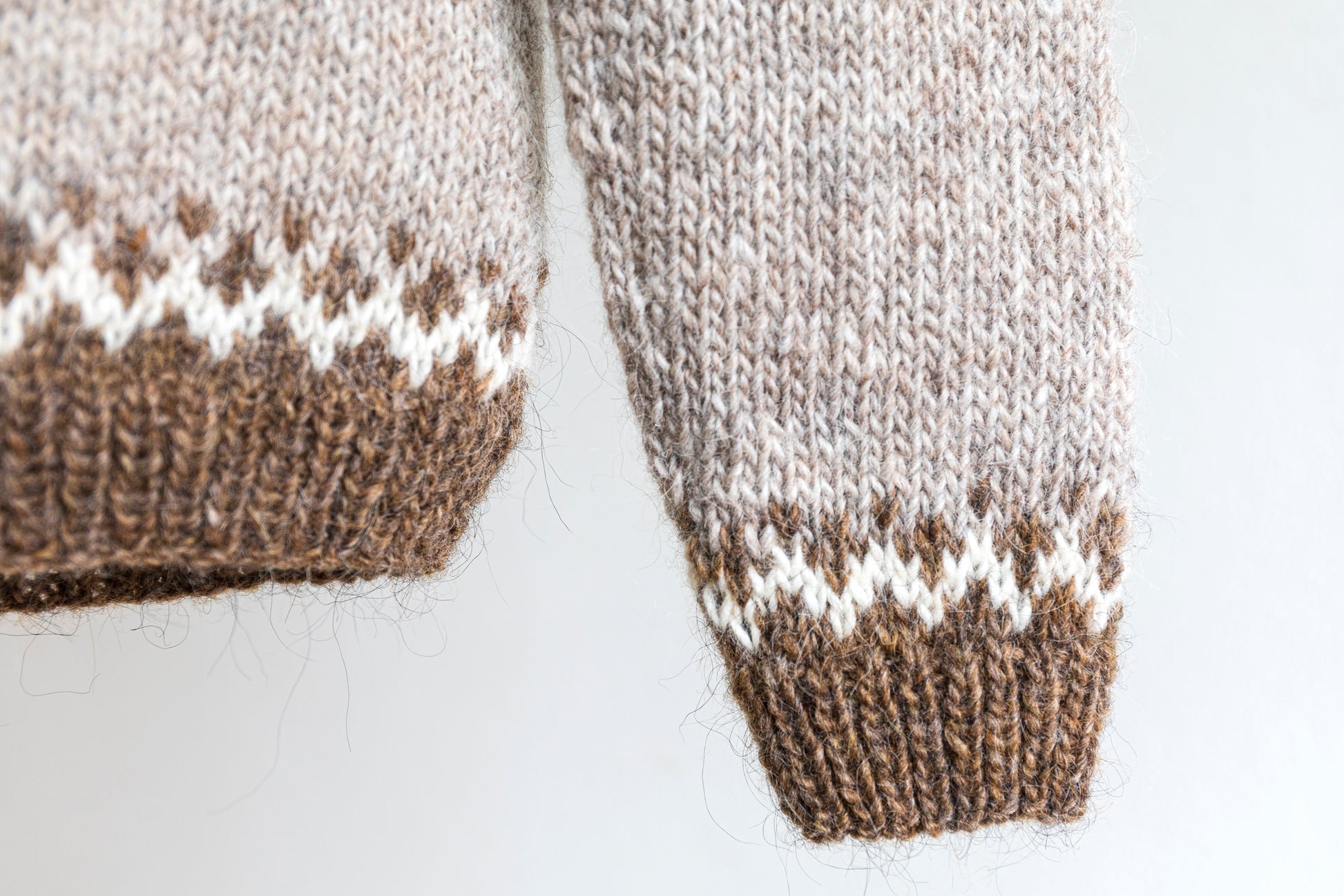 Details of a cuff and a hem of brown and white icelandic wool sweater