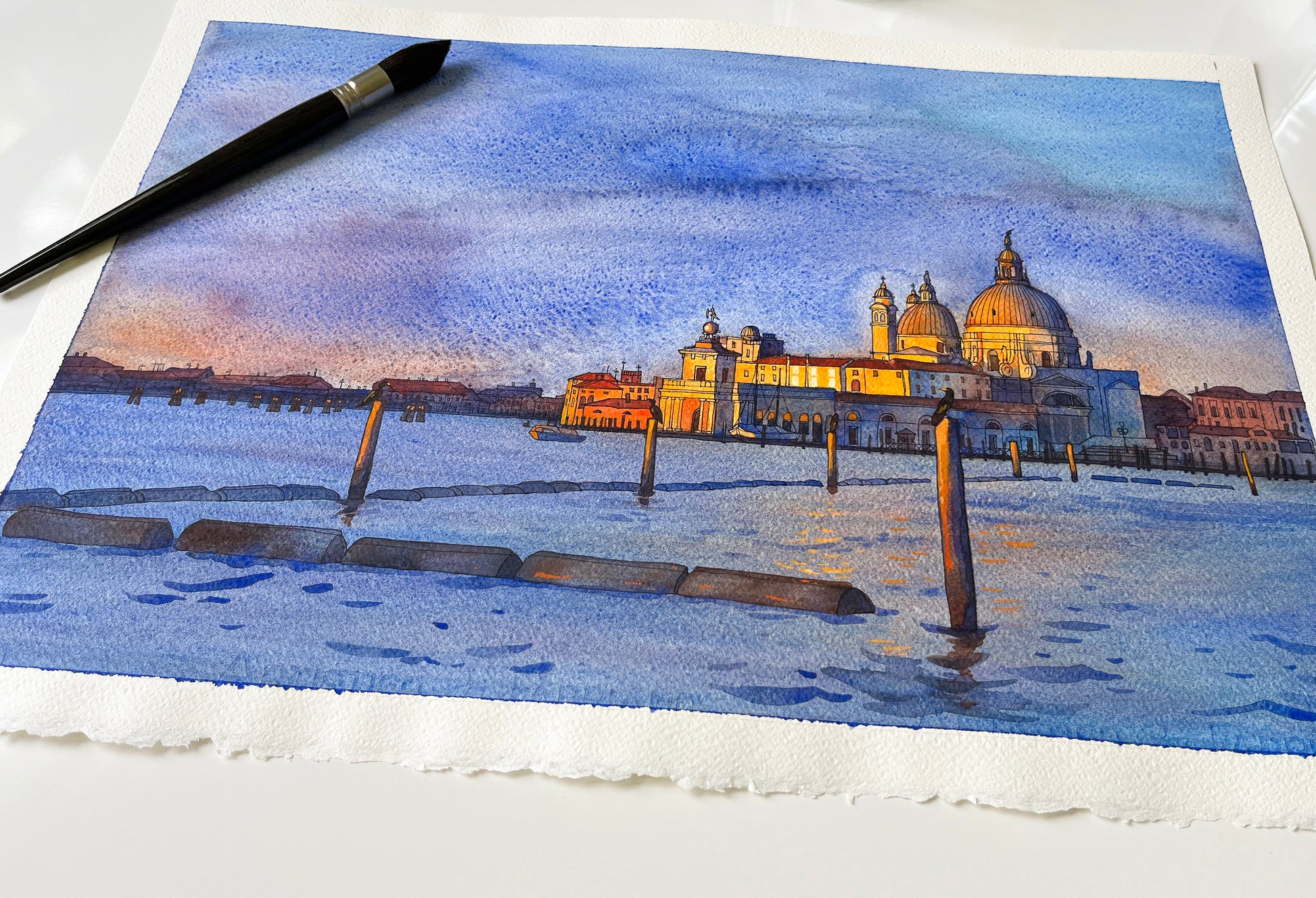 Watercolor painting of Venice San Marco basin at sunrise accompanied by paintbrush