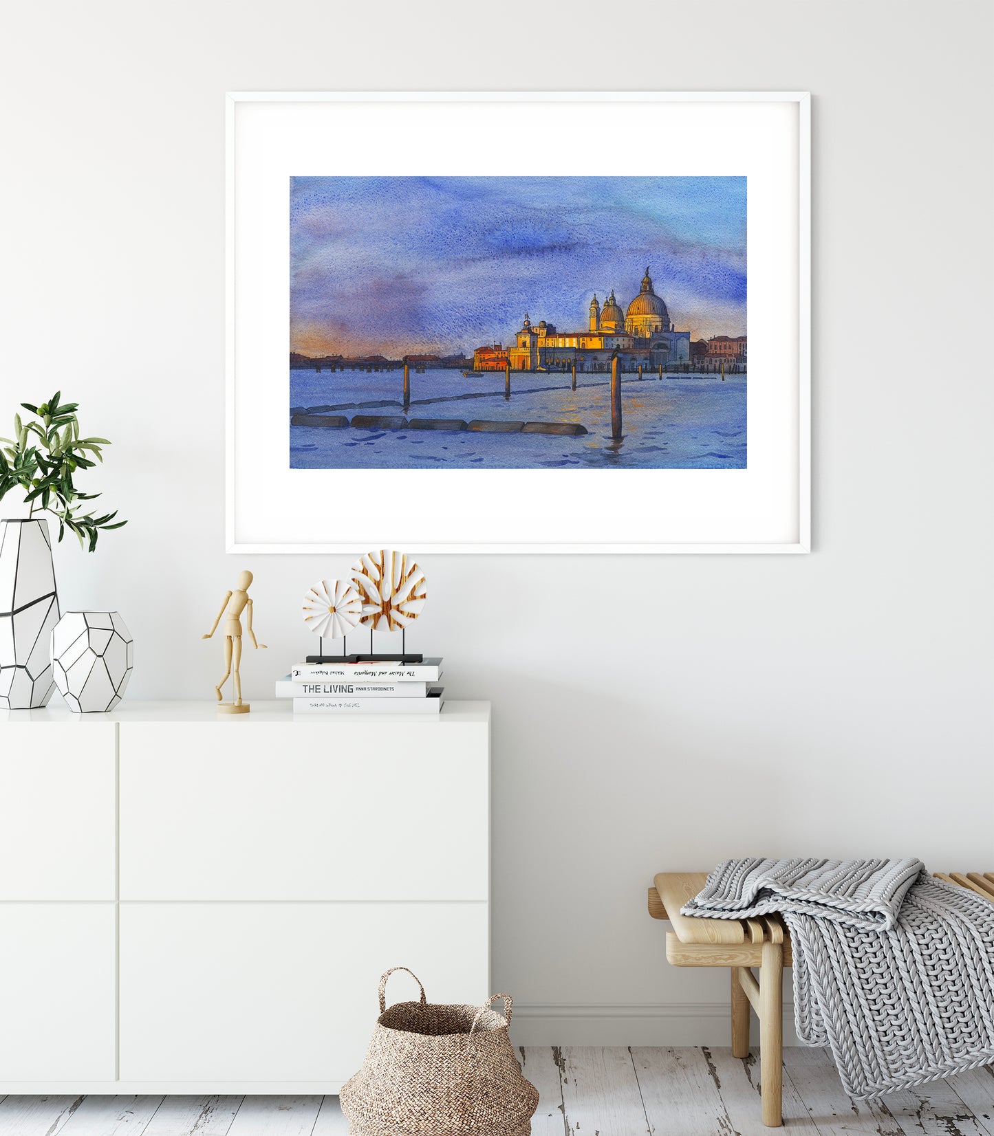 Framed watercolor and ink artwork of a Venice San Marco basin at sunrise with a church on a wall in a room with decor elements.
