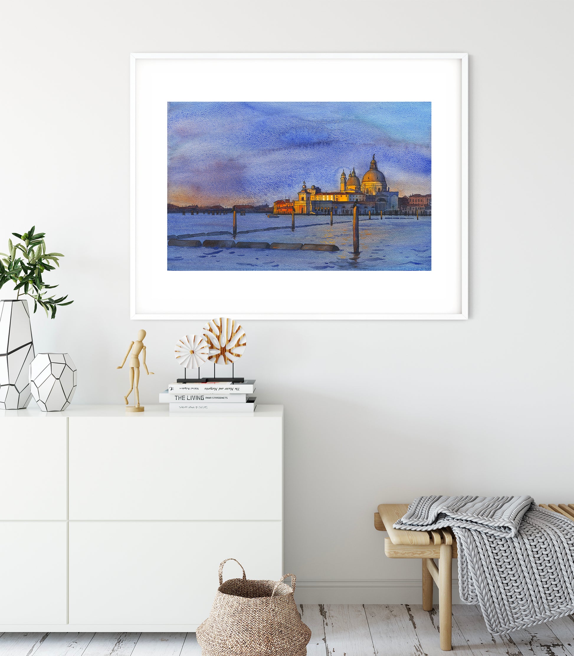 Framed watercolor and ink artwork of a Venice San Marco basin at sunrise with a church on a wall in a room with decor elements.