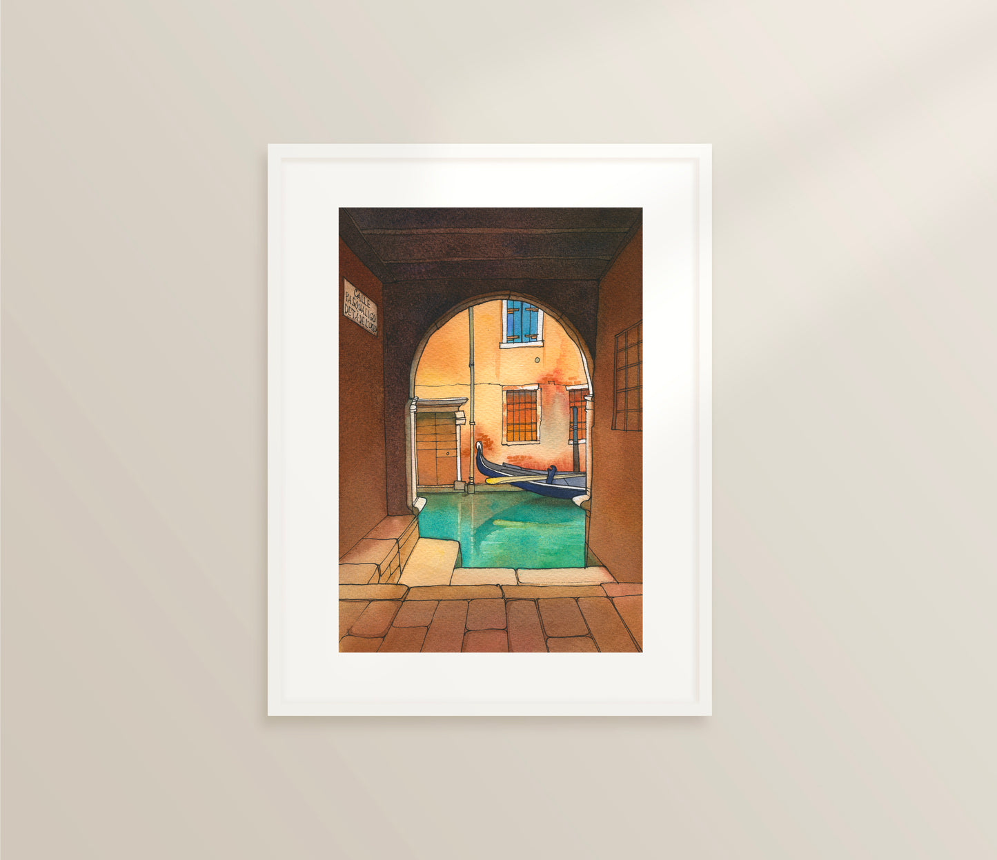 Framed watercolor and ink artwork of a venetian canal scene with a gondola on a beige wall.
