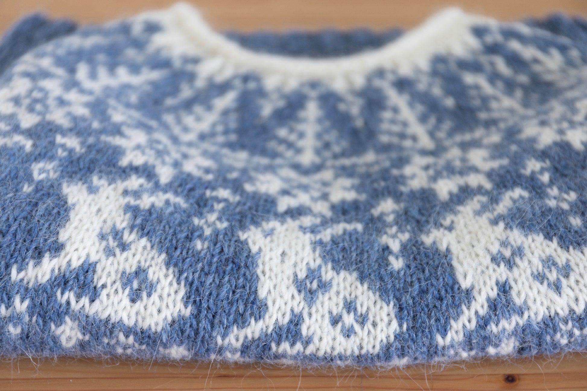 Close-up of a folded hand-knitted wool sweater with bunnies motif in bue and white