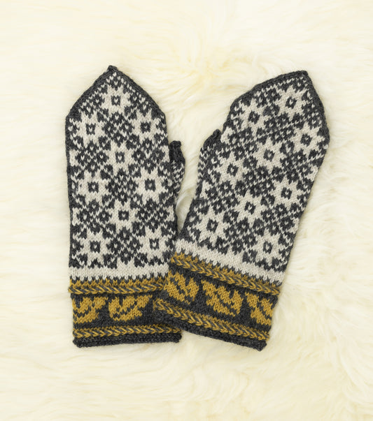 Front view of a pair of black, white and yellow hand-knitted mittens with traditional Estonian pattern on a white fur background