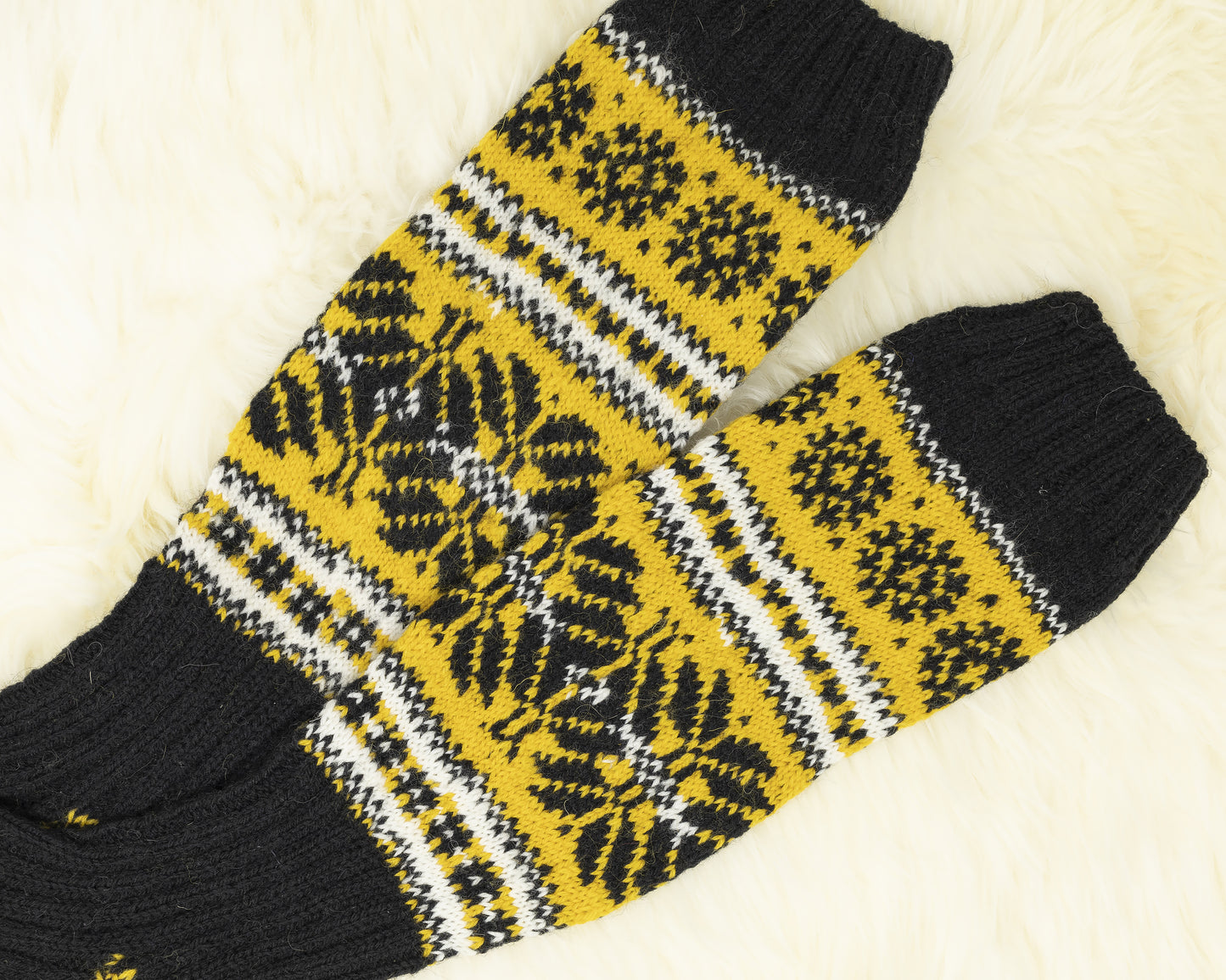 Legs of a pair of black, yellow and white hand-knitted Estonian socks on a white background