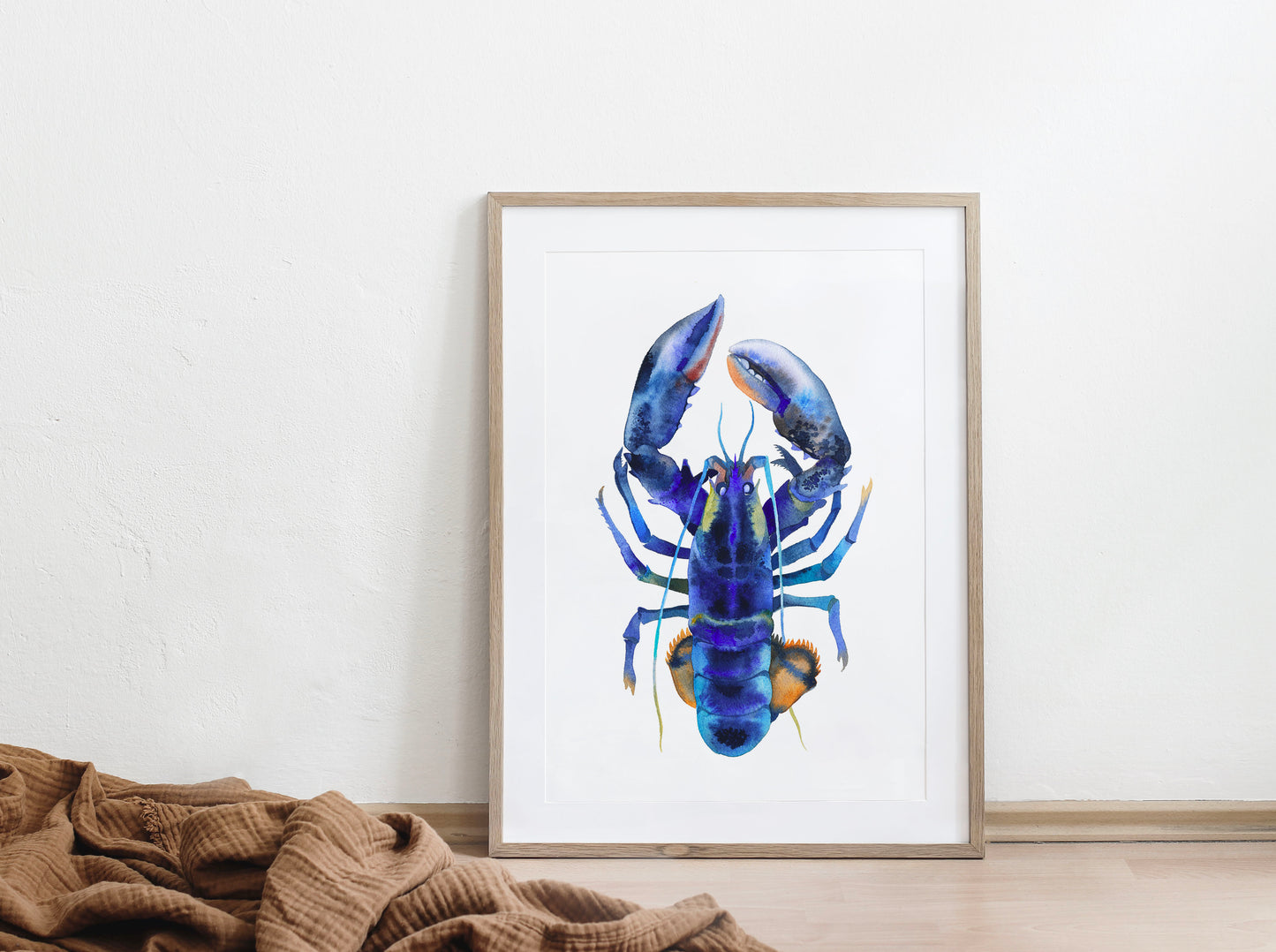 Framed blue lobster watercolor art print displayed on a floor