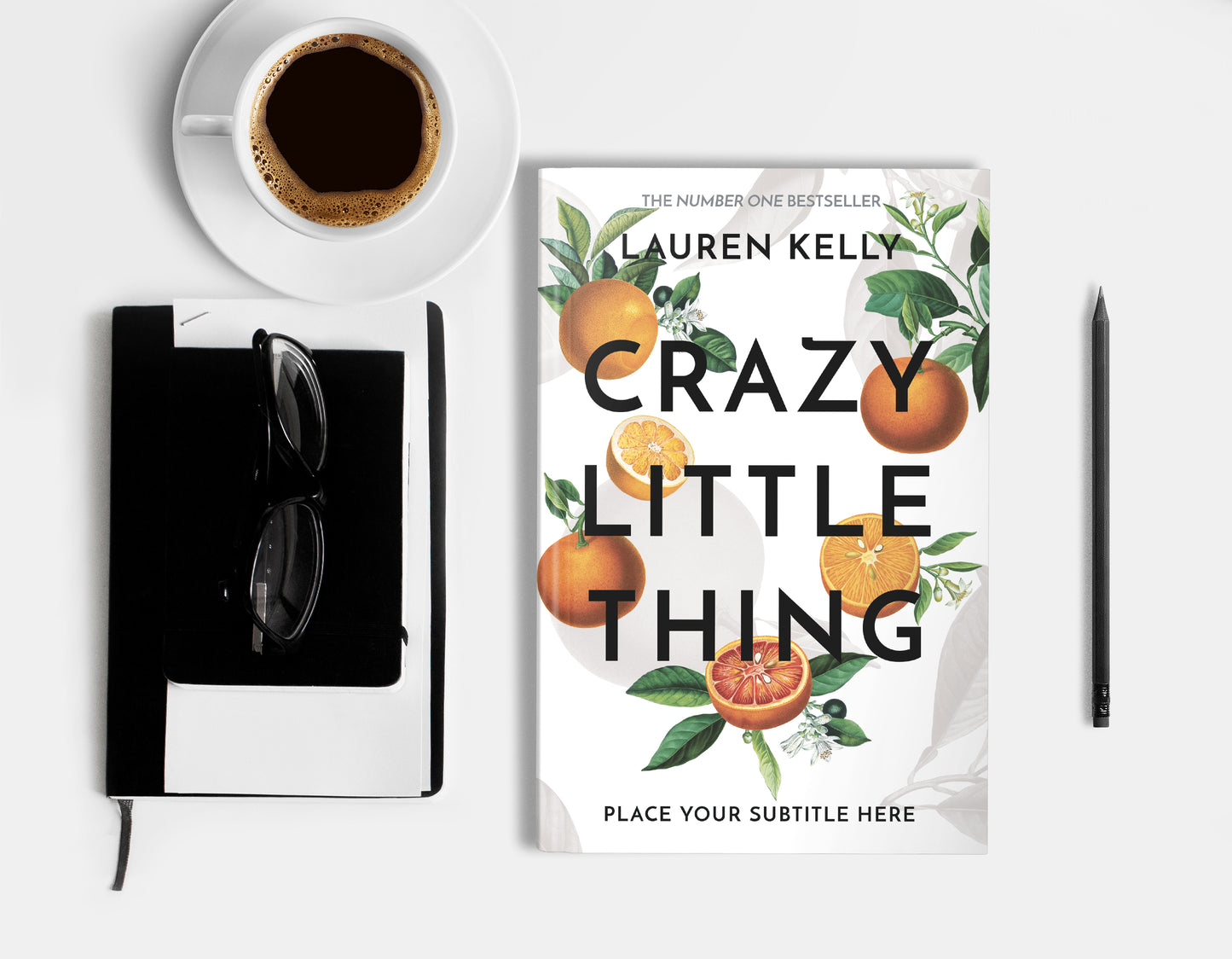 A hardcover book featuring vintage botanical oranges illustrations on a white background, displaying on a white surface with cup of coffee, a pencil, a notebook and glasses