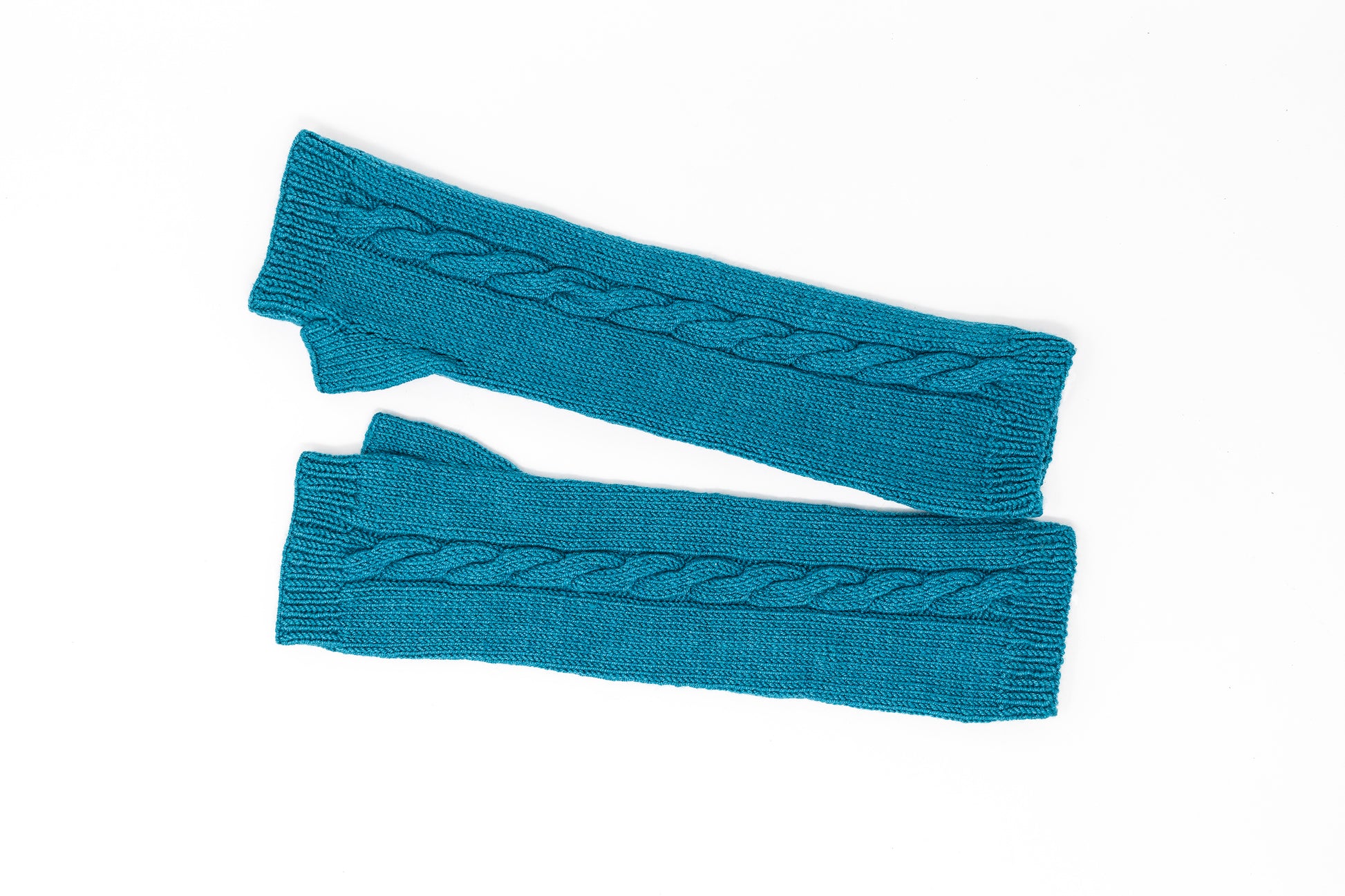 A pair of cable-knit fingerless gloves in teal merino wool laid flat on a white background