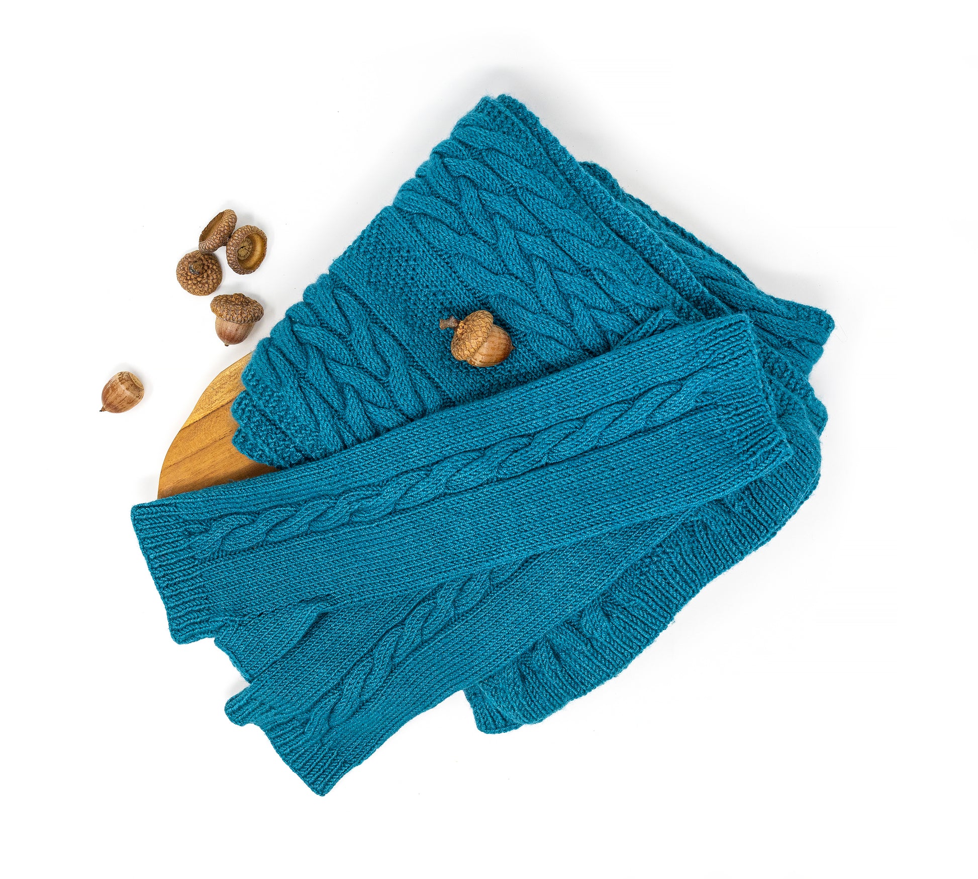 Cable-knit fingerless gloves and matching scarf in teal merino wool on a white background