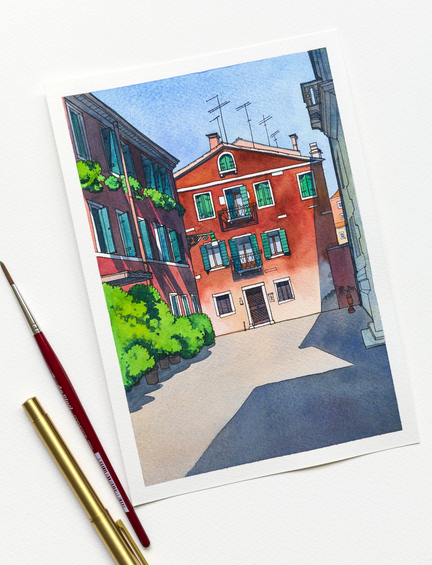 Original watercolor artwork of Calle Sechera in Venice, Italy, accompanied by art supplies