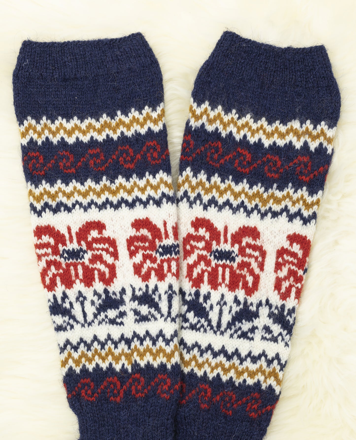 Legs of floral Estonian hand-knitted knee-high socks in blue, red and white on a light background