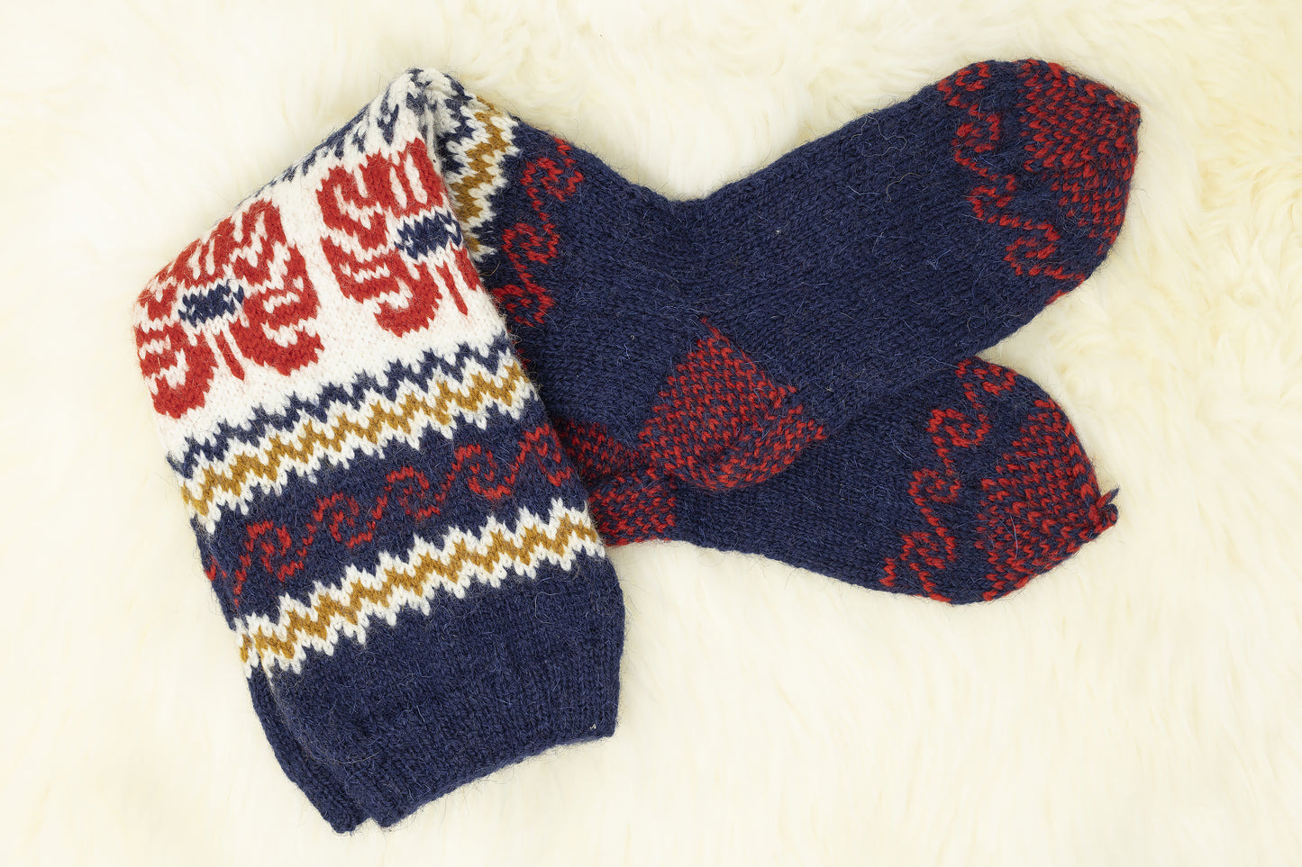 Pair of floral Estonian hand-knitted knee-high socks in blue, red and white on a light background