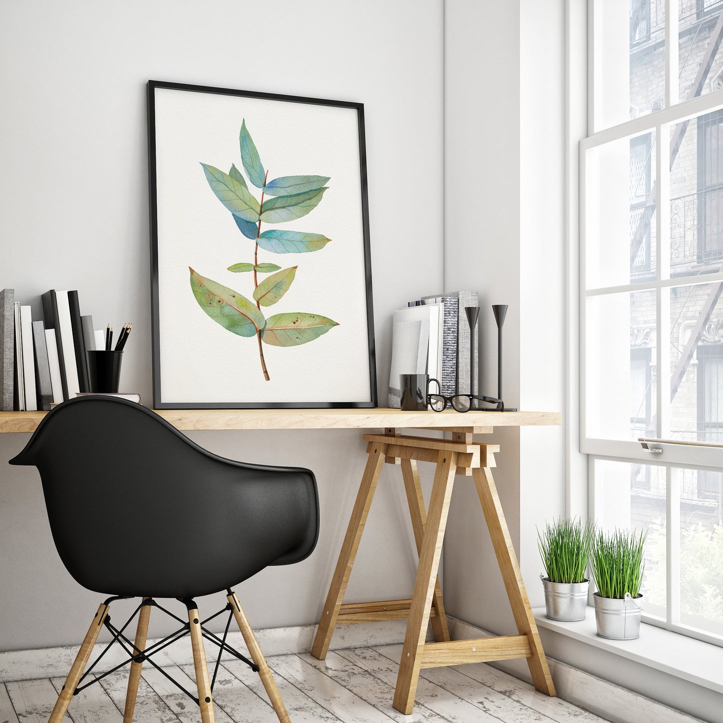 Eucalyptus branch watercolor print in a black frame, displayed on a table in a home office