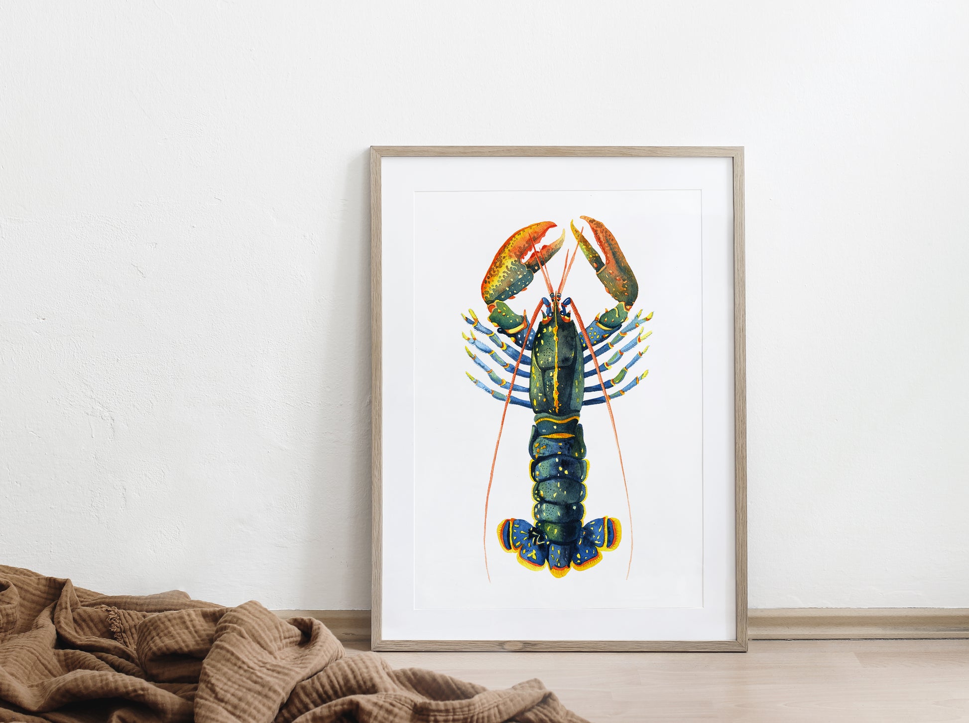 Framed european lobster watercolor art print, displayed on a floor