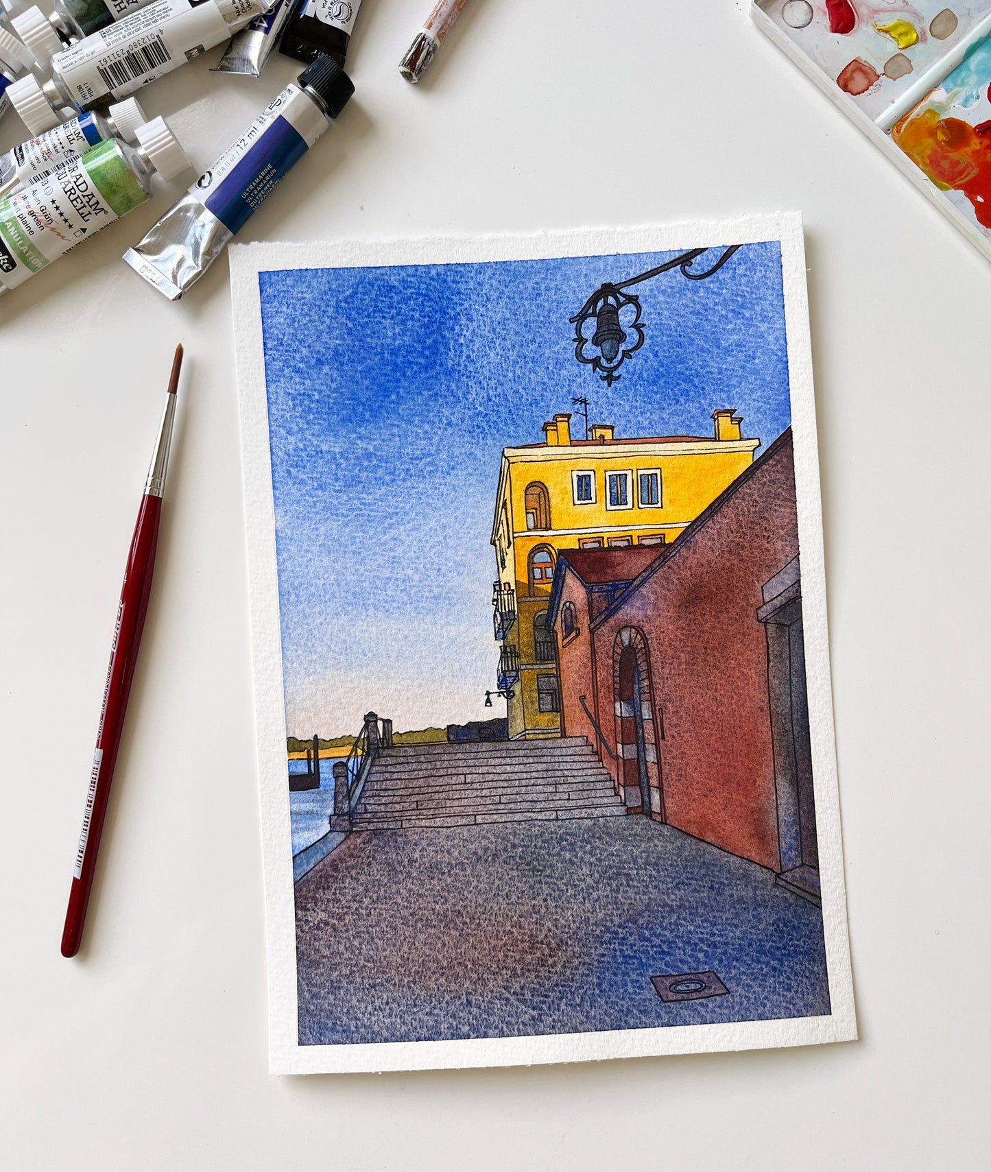 Original watercolor and ink artwork of Venetian Fondamenta Santa Giustina, laid flat with art supplies.