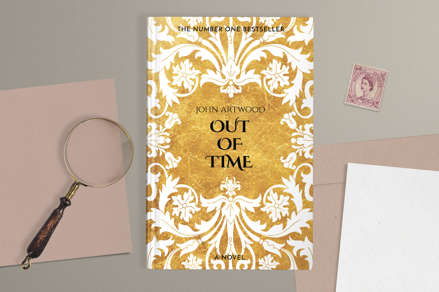 A hardcover book featuring white baroque ornament of a gold background, displaying on a gray surface