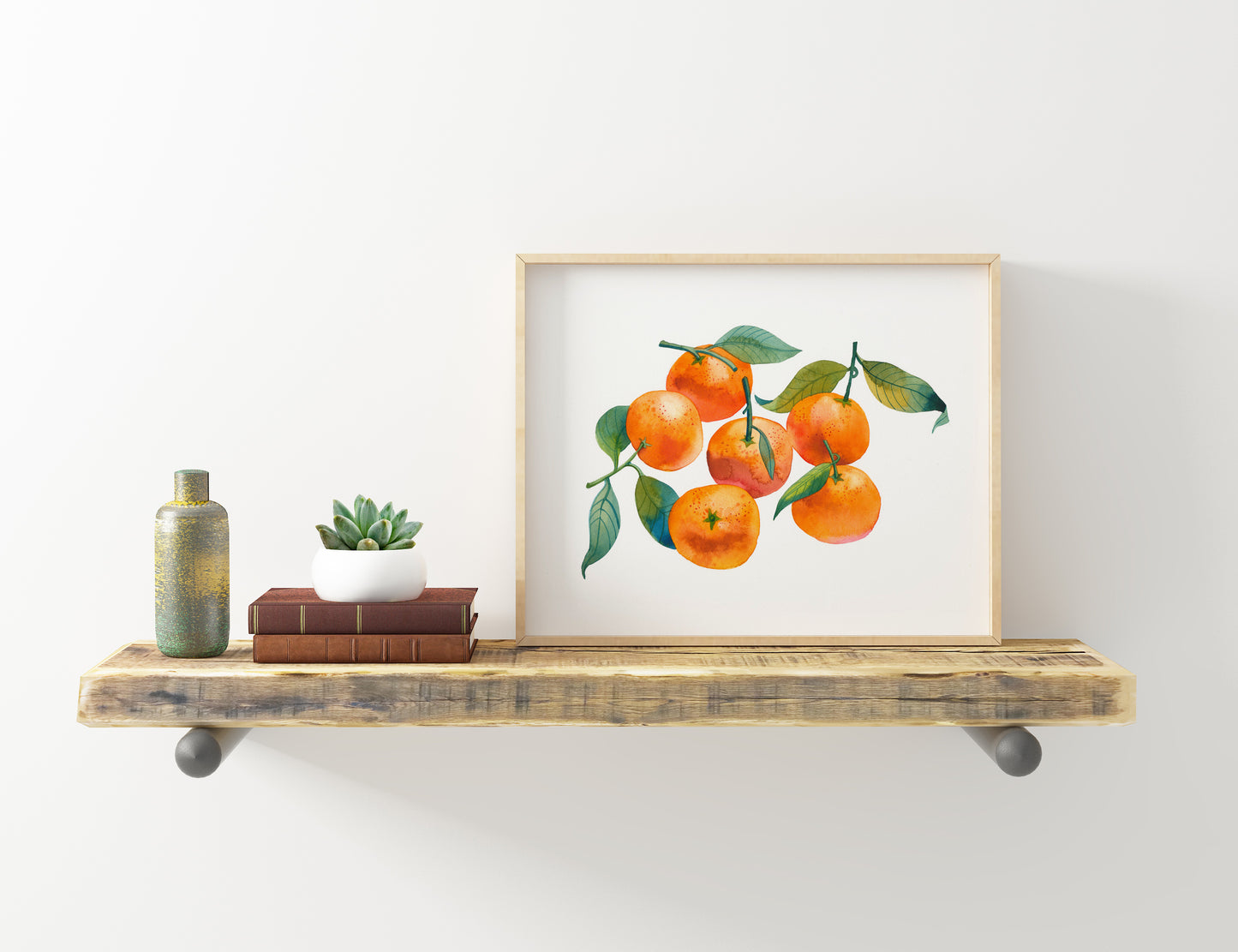 A small framed watercolor print of orange mandarins with green leaves