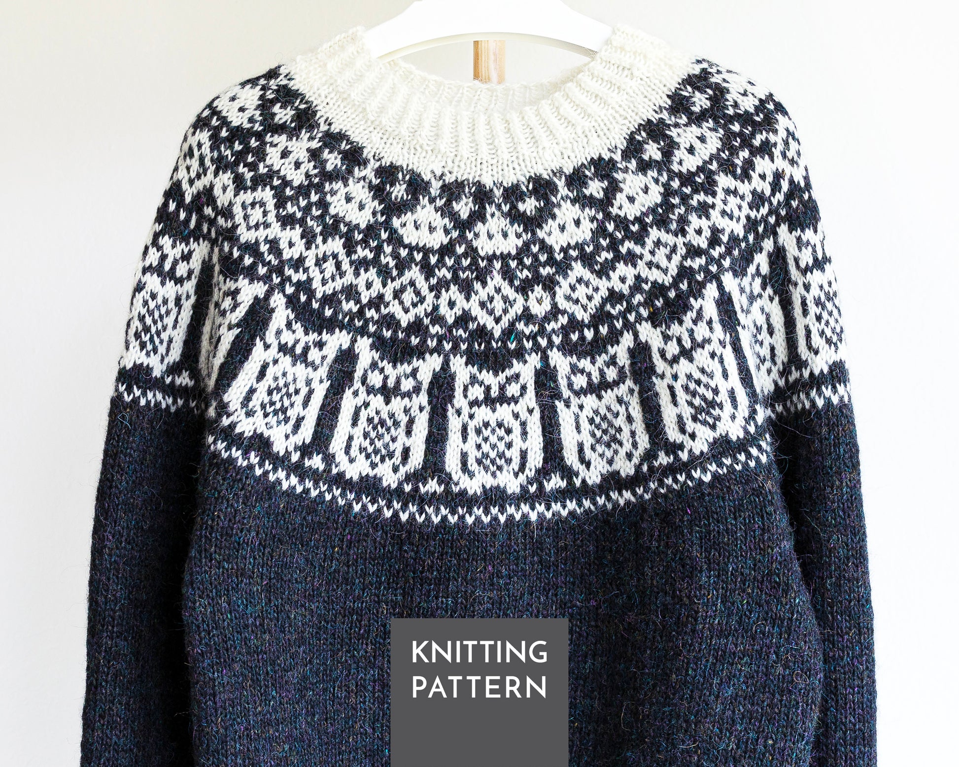 A black and white knitted sweater with Nattuggla Nigh Owl pattern, shown hanging on a white hanger against a white background. A dark gray label at the bottom reads 'KNITTING PATTERN'.
