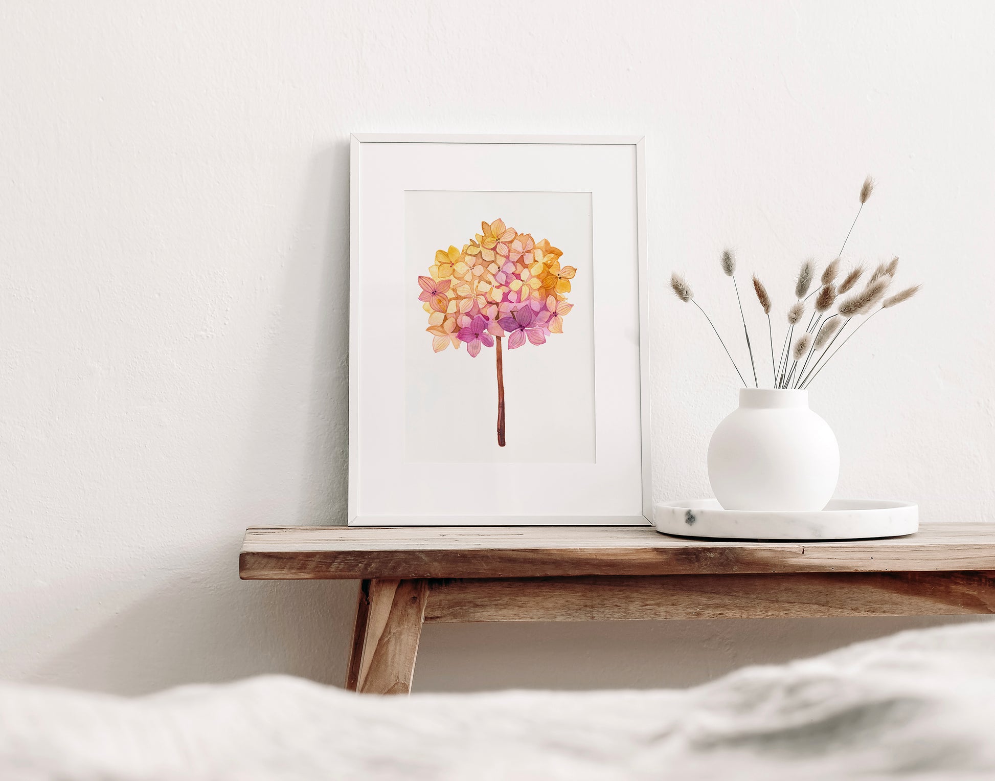 Pink hydrangea dried flower ball watercolor print in a frame on a wooden table