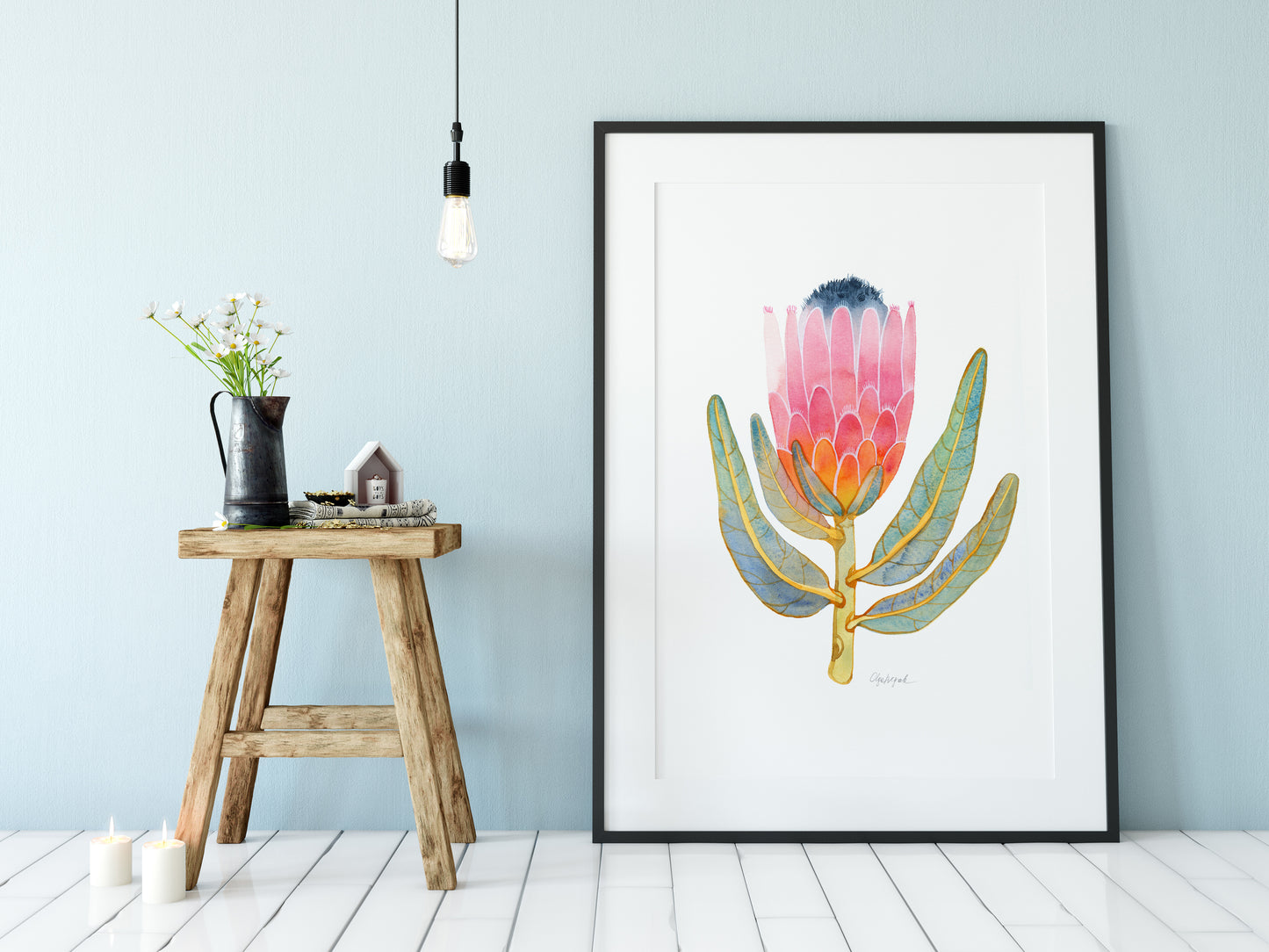 Framed pink King protea watercolor art print displayed on a floor