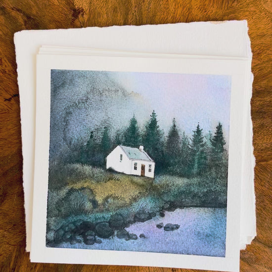 Four watercolor paintings featuring Scottish Highlands — Glencoe, the Pink House at Loch Glass (Culzie Lodge), Allt Dearg cottage on the Isle of Skye, and a remote stone croft near Applecross, displayed on a wooden background