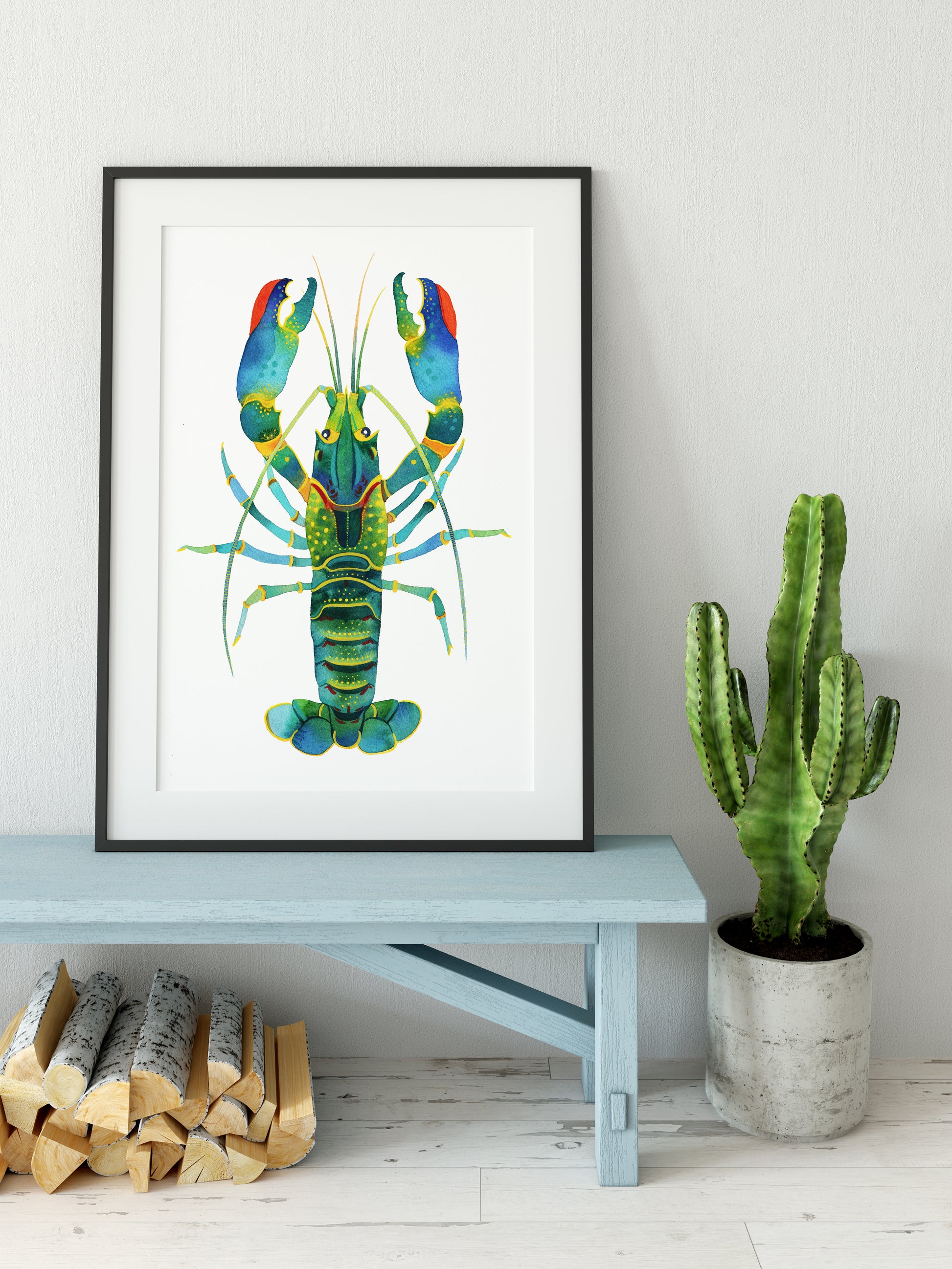 Red Claw Crayfish watercolor art print in a black frame, displayed on a wooden bench