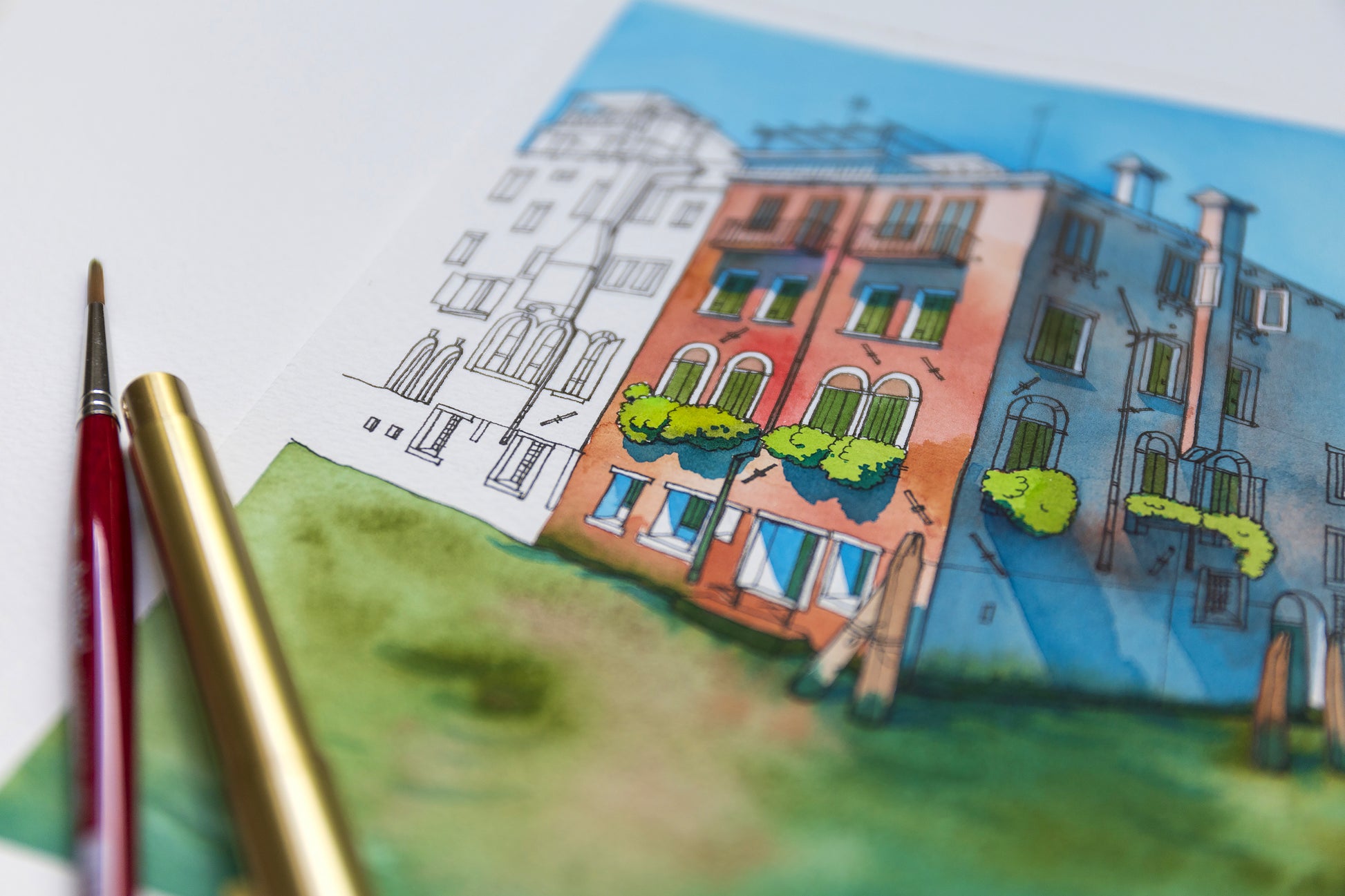 Close-up of watercolor and ink illustration of Rio della Misericordia in Venice with paintbrush and pen on a white surface