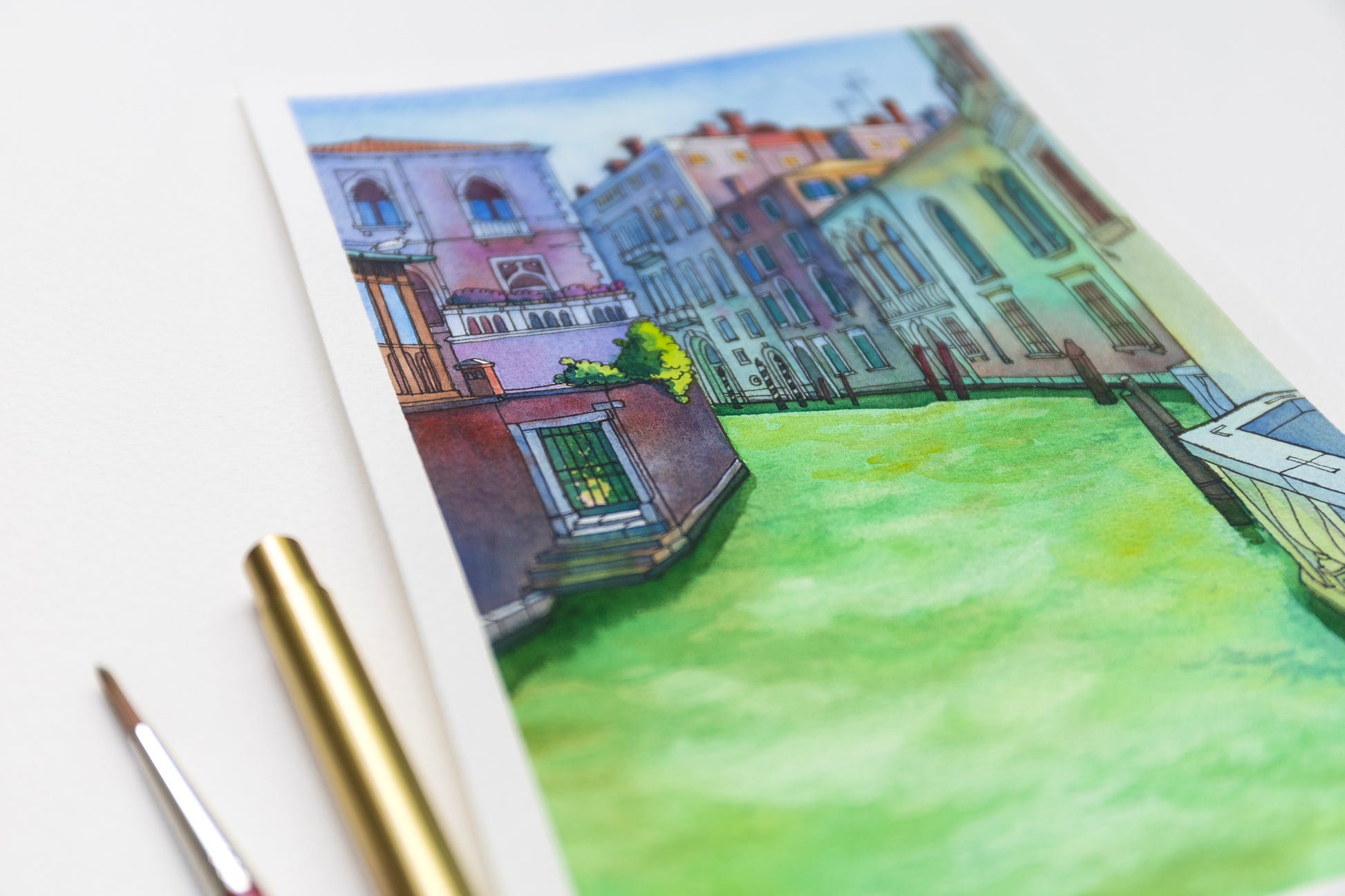 Close up of a watercolor painting of Rio di San Polo in Venice scene, accompanied by a gold pen.