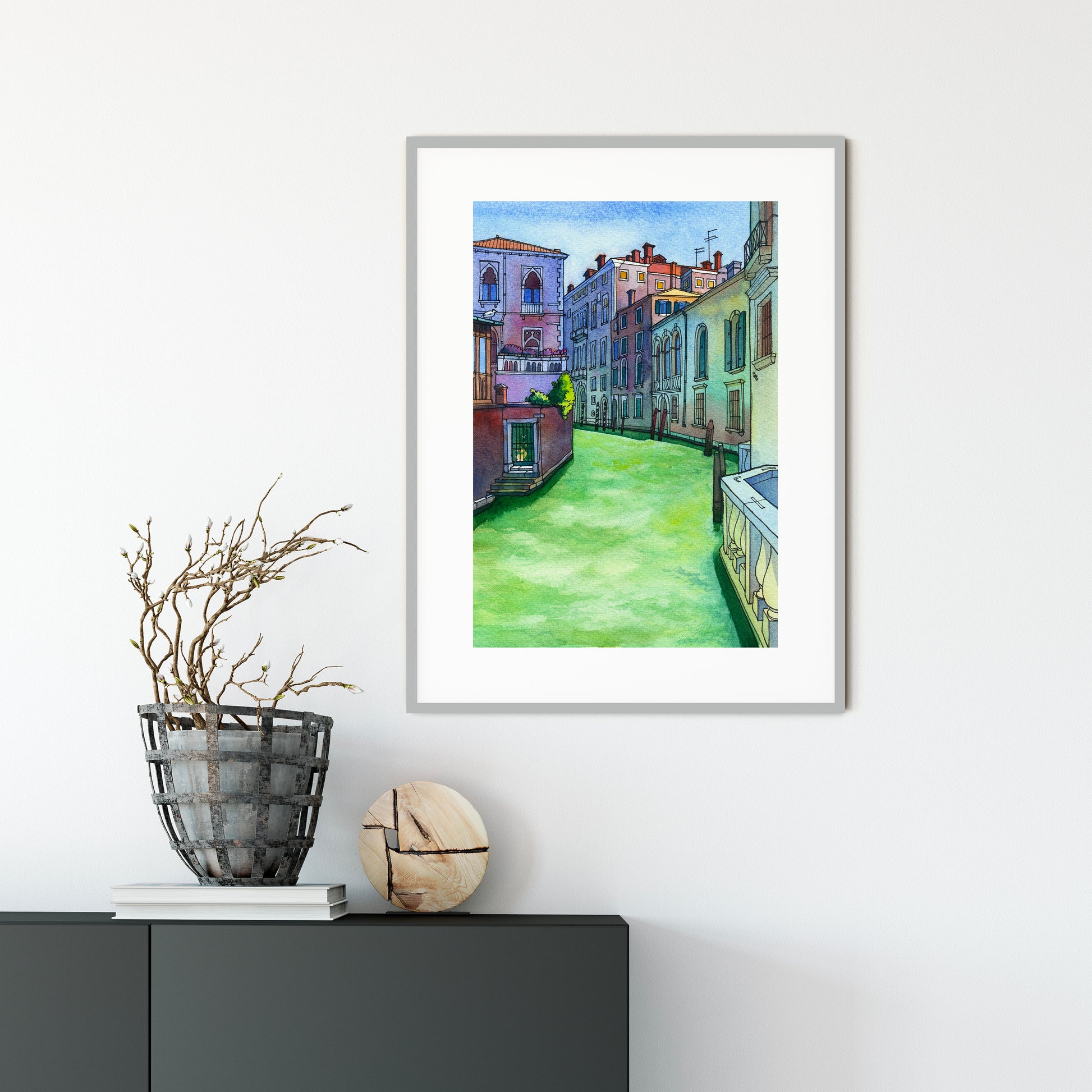 Large framed watercolor and ink artwork of a Rio di San Polo in Venice scene, displayed on a white wall above a dark surface with decorative items.