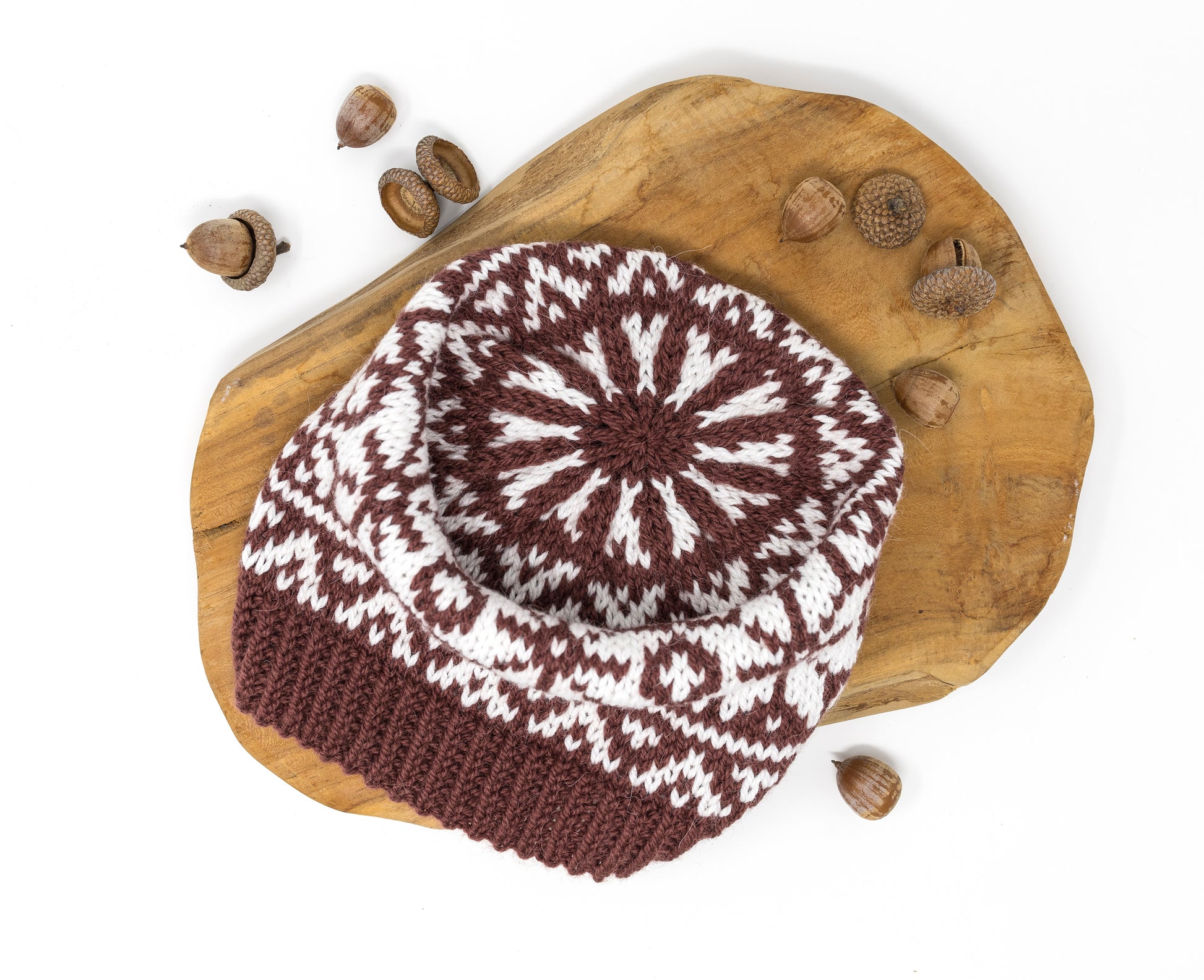 Close-up of a crown of a knitted beanie hat with a brown and white Selburose pattern.