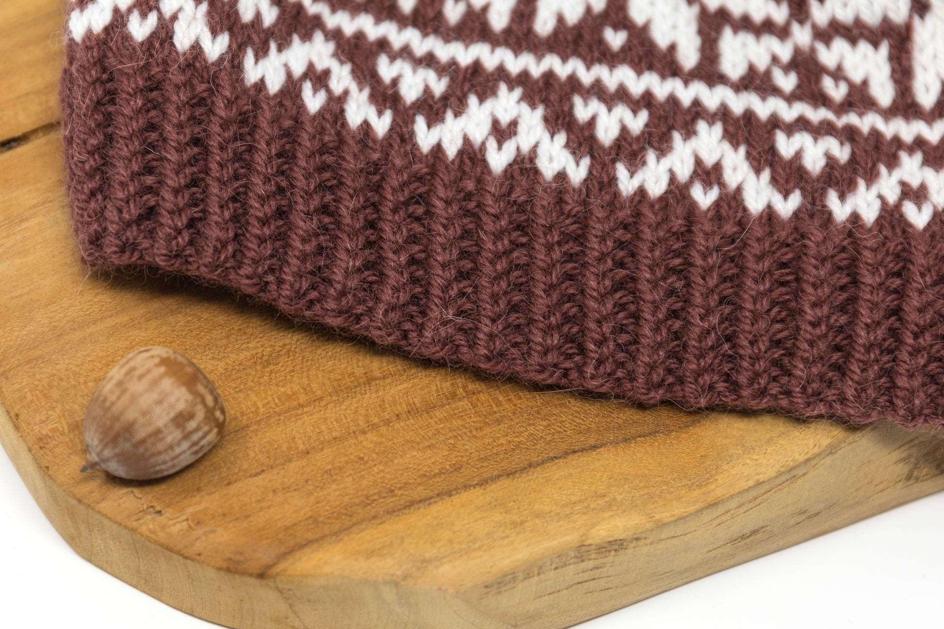 A close-up of a twisted ribbing of a brown and white hand-knitted Selburose hat.