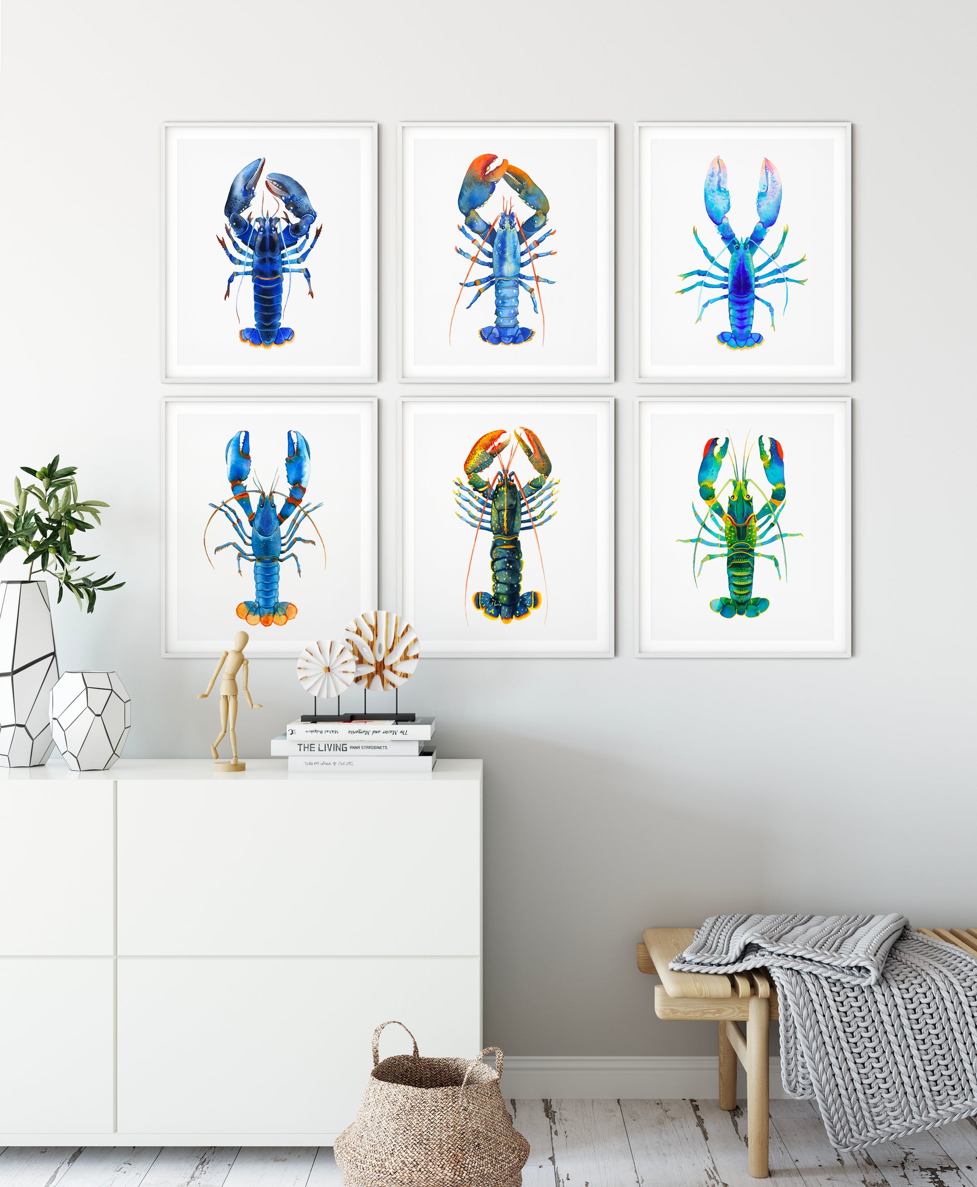 Six framed blue lobster watercolor art prints displayed on a light gray wall above a white cabinet.