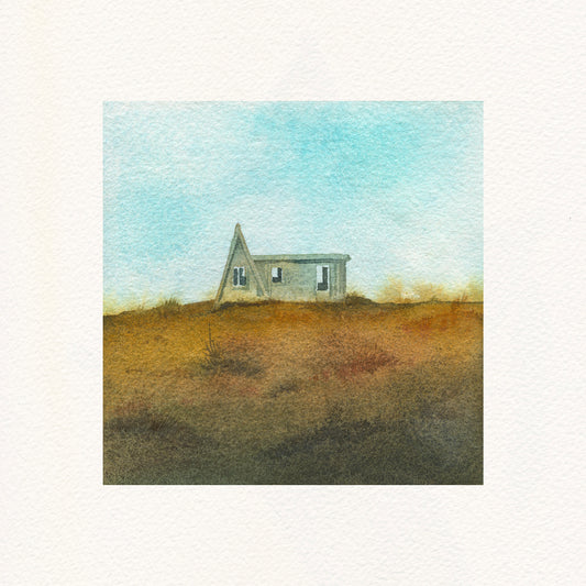 Small a-frame house on a hill with a blue sky